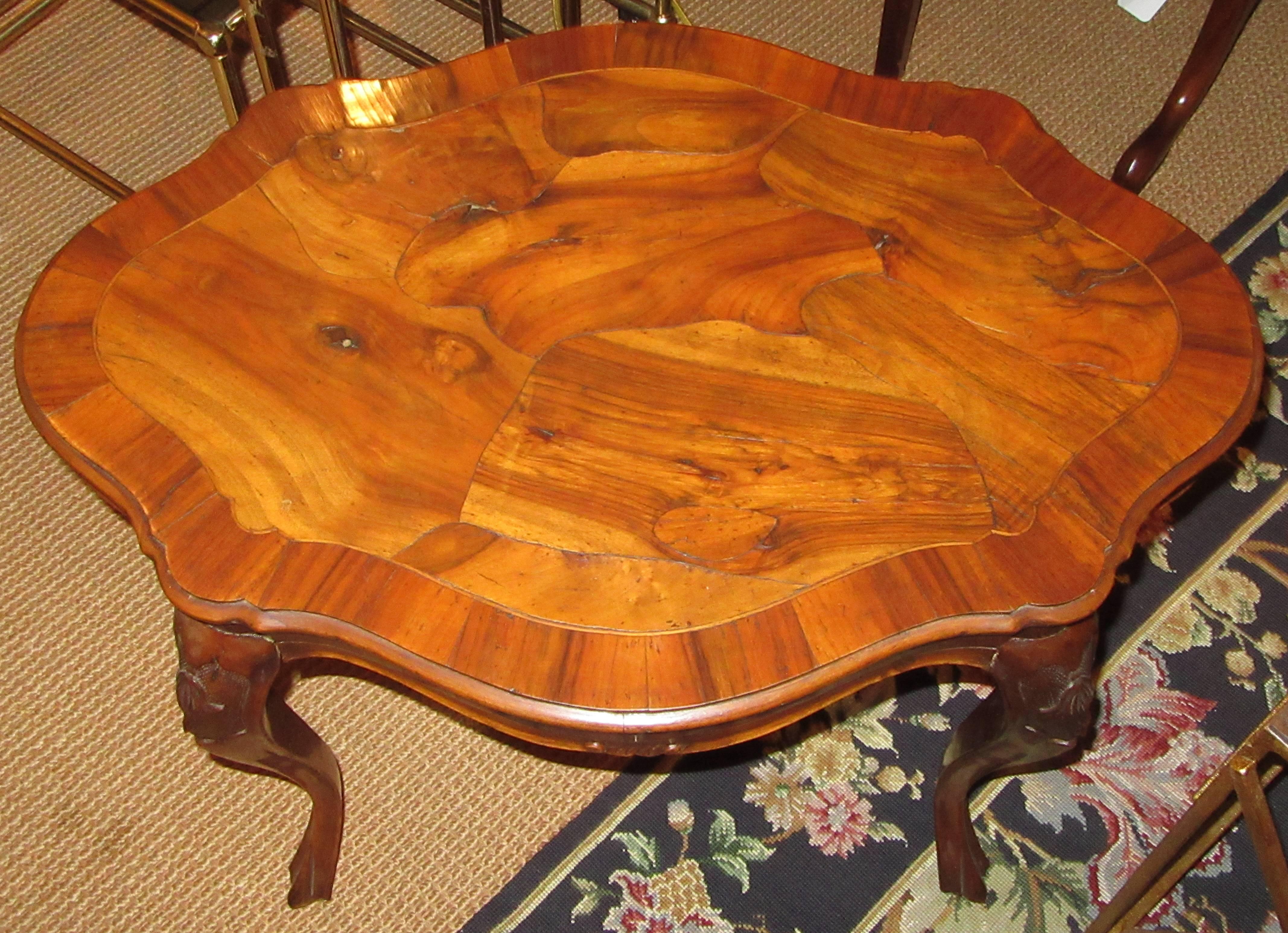 A small wood end or coffee table with a unique top of abstract form marquetry veneer, emphasizing the beautiful grain of the wood (walnut).