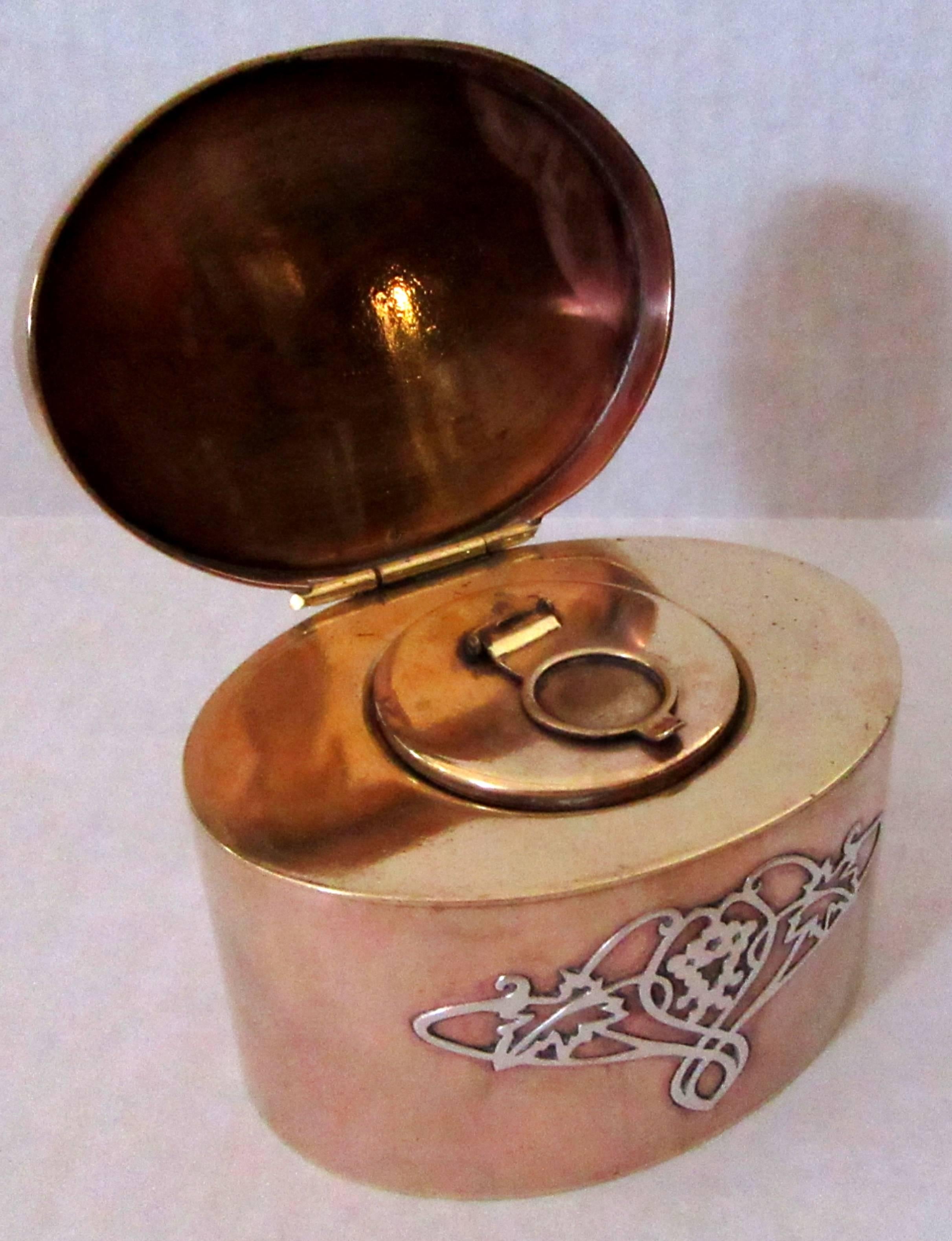 An oval form inkwell of copper decorated with sterling silver in and Arts and Crafts style design. A coordinating oval pen tray, marked STERLING.
