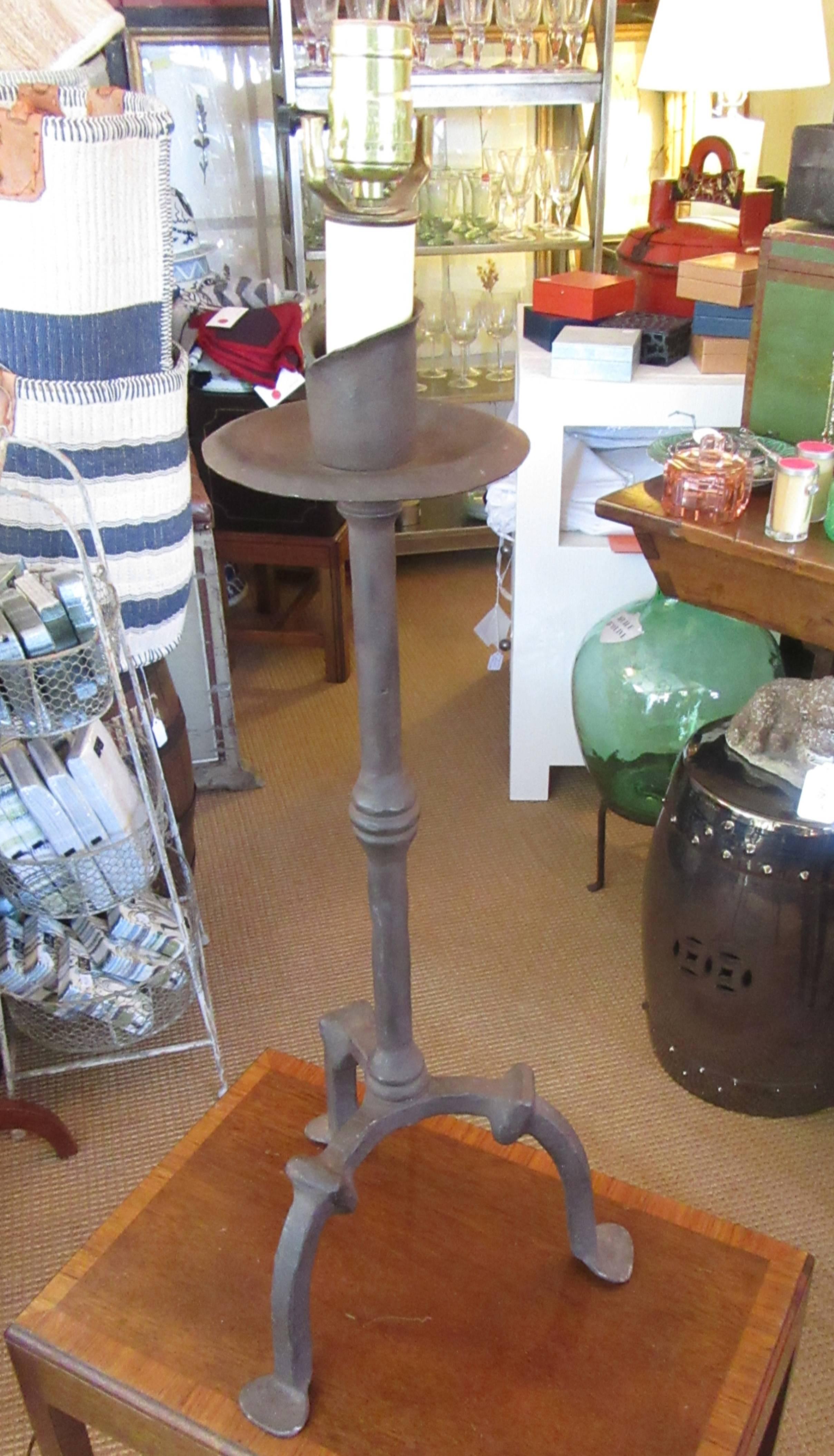 A substantial wrought iron single light table lamp on a tripod base.