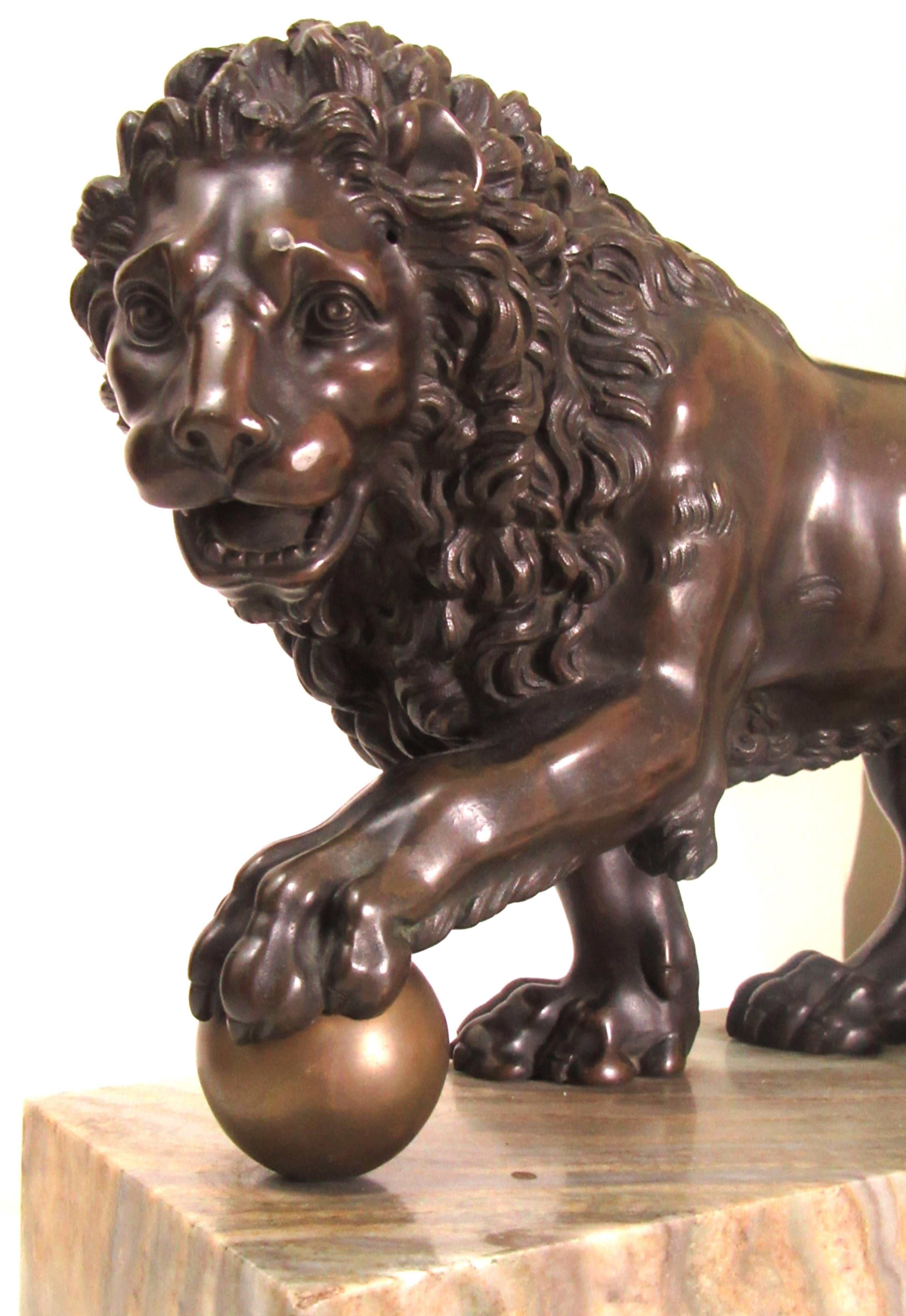 A nicely patinated cast bronze statue of a Medici lion supported on a plinth of two varieties of marble.