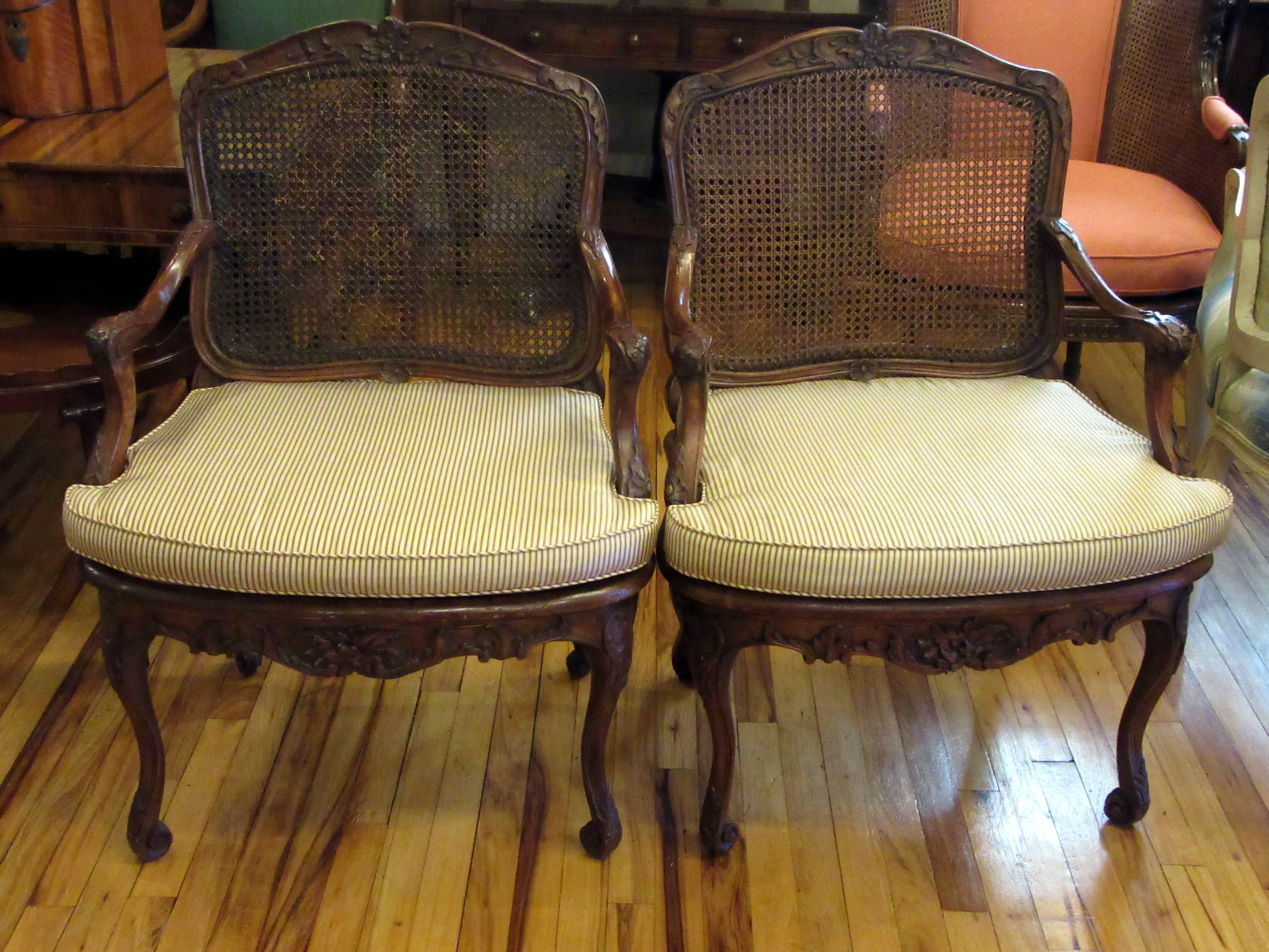 A pair of carved beechwood, caned back and seat armchairs with upholstered cushions. One chair is signed L. Cresson. During the 18th century the Cresson family produced a remarkable number of furniture makers. One of the most prominent Cressons was
