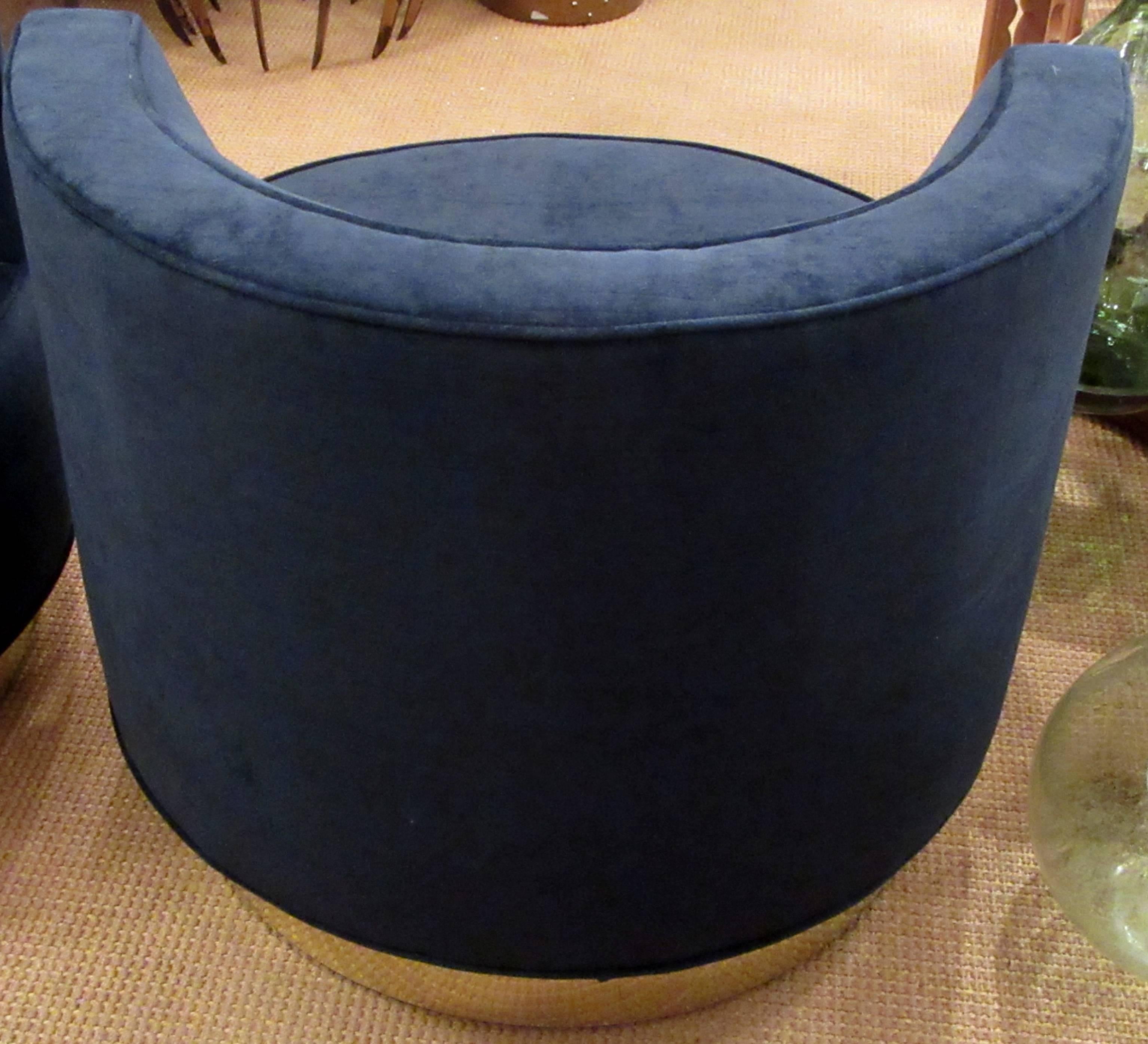 A pair of newly upholstered swivel chairs on round platform bases that are clad in brass.