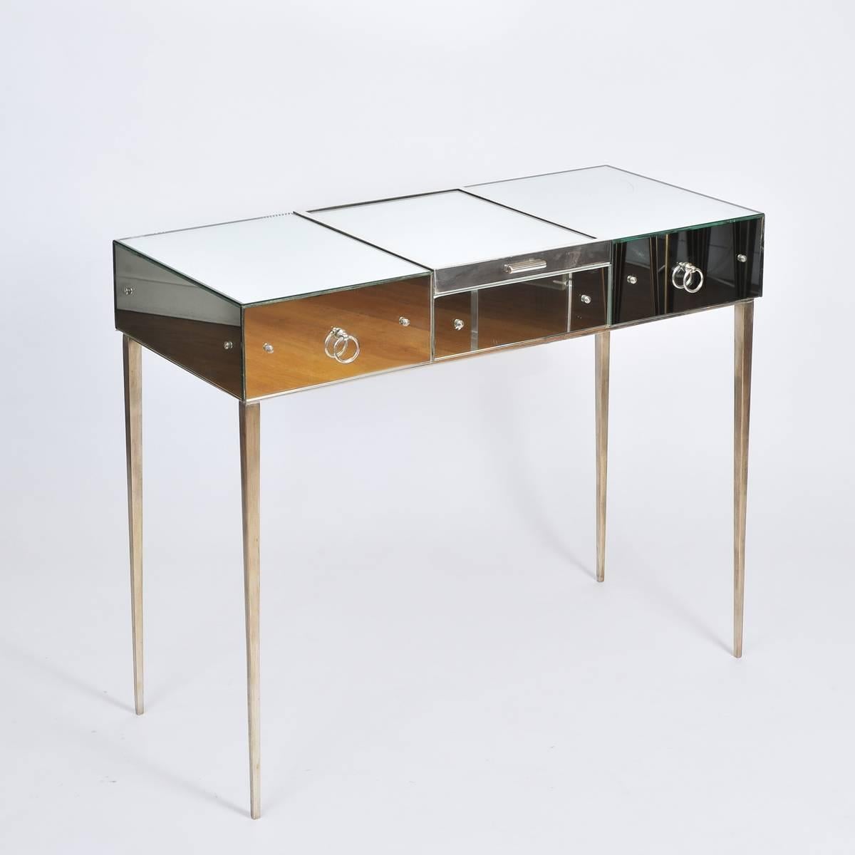 1930s mirrored dressing table, one of only two examples known, designed by Jean Michel Frank for Comté. The triptych configuration of two drawers and a central compartment accessed by lift-up vanity mirror, is all supported on exquisitely slender,