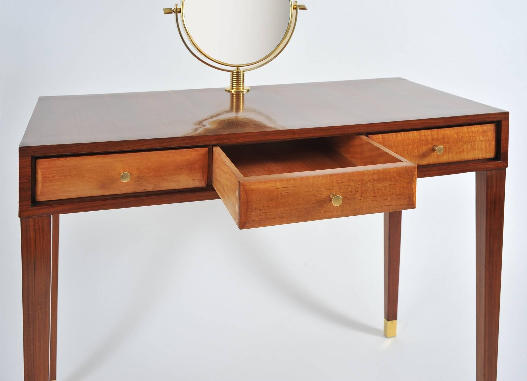 Three-drawer vanity table in cherrywood with lighter fruit wood drawers, integrated brass circular mirror on a fluted brass base, the whole standing on square tapering wood legs with brass feet.
The height given below is that of the table top. The