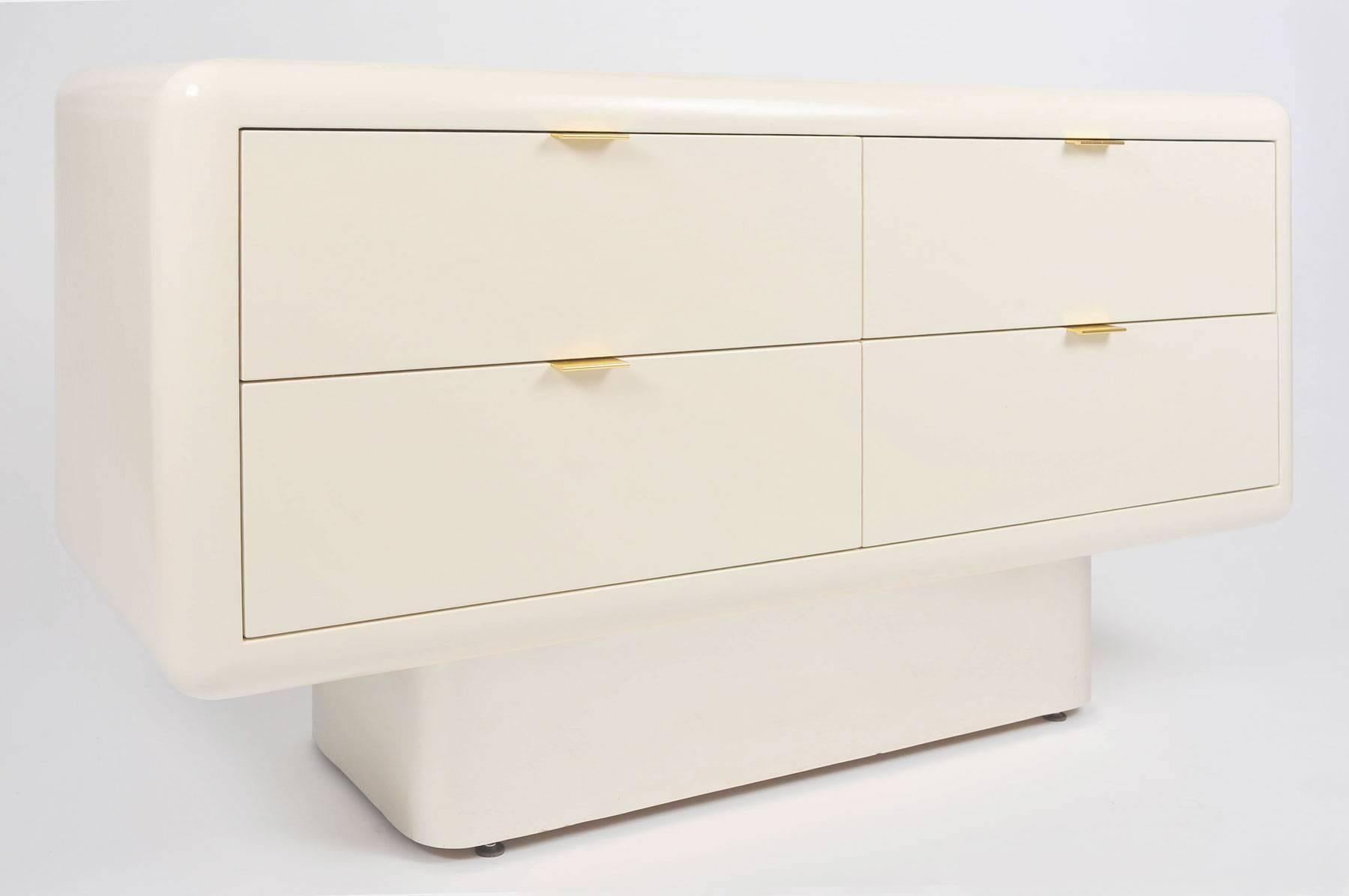 Fabulous smooth, curved-edge, cream, lacquered chest-of-drawers designed by Steve Chase. Four drawers with simple brass handles. Sits on inset silver metal curved base.
Pair of matching night stands also available.