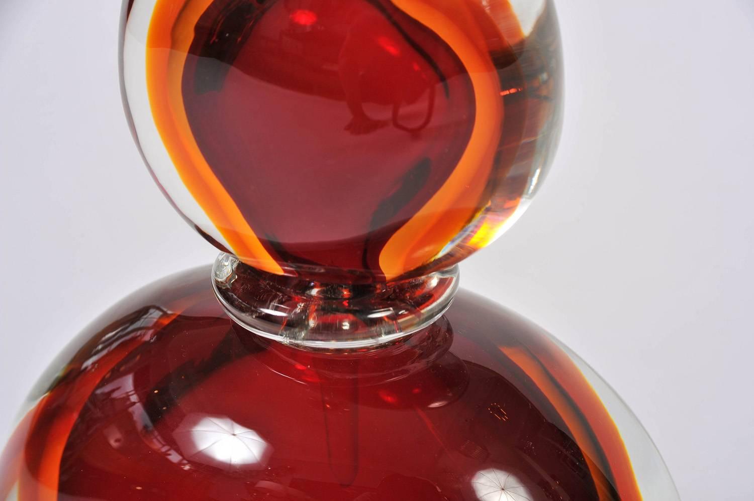 Super-sized perfume bottle and stopper in smoothly sculpted red, amber and clear Murano glass.