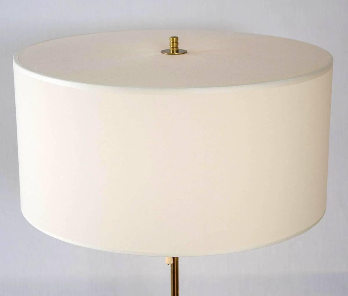 Brass table lamps with slim supports emanating form conical bases holding their original custom-made drum shades in off-white linen, stamped: 'Bergbom' on underside.
