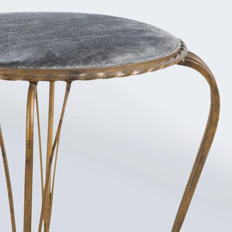Elegant gilded iron stools, newly-upholstered in light shades of grey/blue, with scrolled legs – sold individually