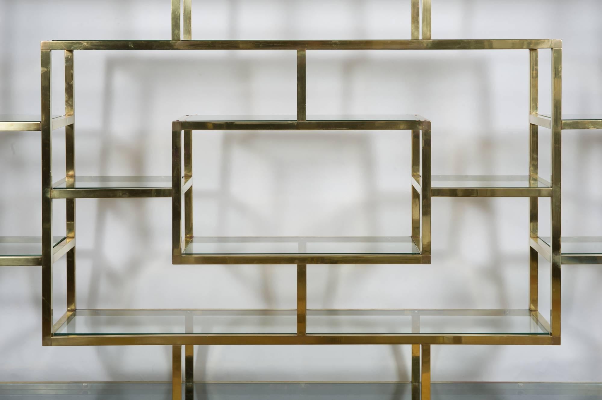 Wide symmetrical shelving system by Romeo Rega. Polished brass frame with clear glass shelves sit on black lacquered base. Would make a perfect bookcase, display shelving or floating room divider.