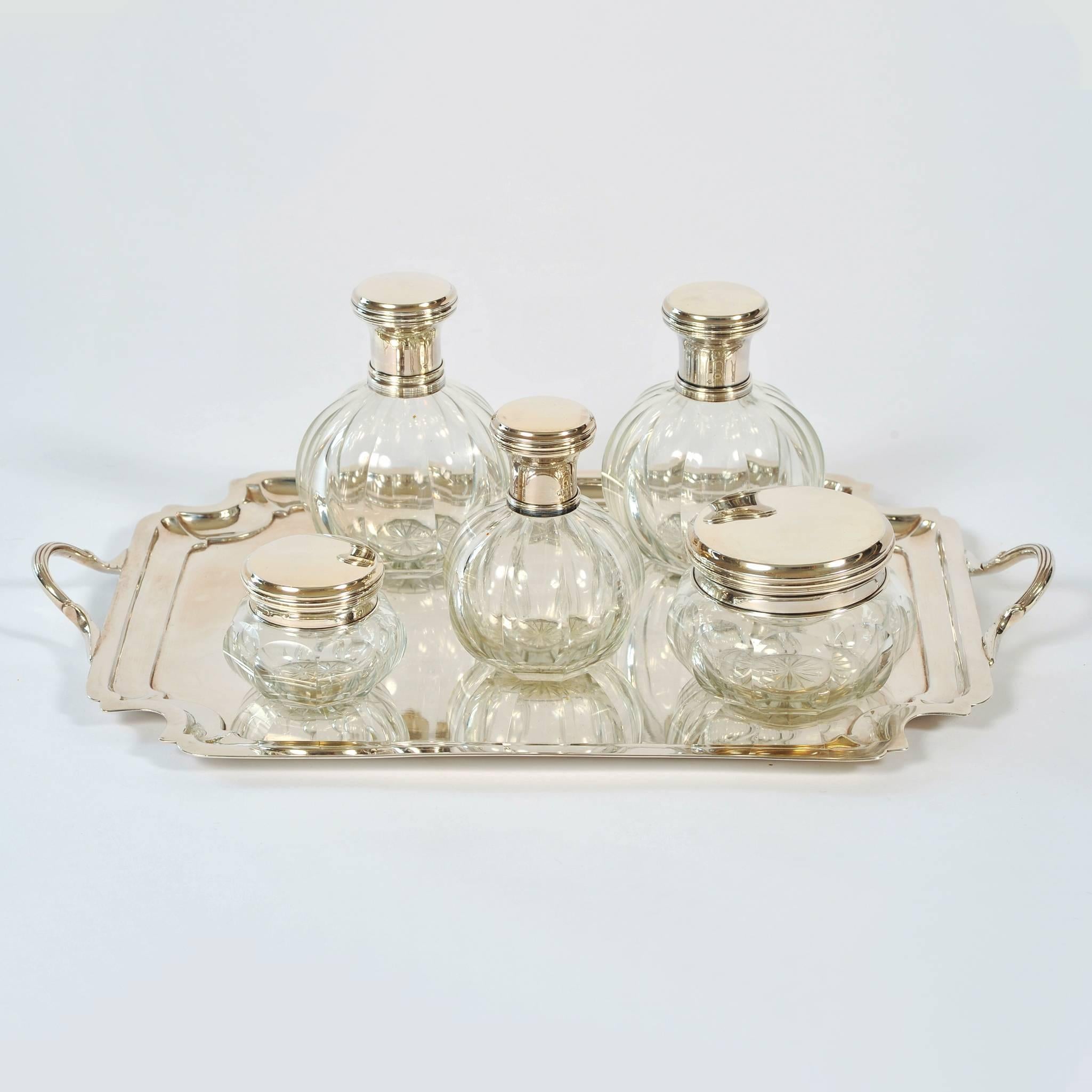 Five-piece set comprising of three scent bottles with their glass stoppers intact, one powder puff and one cold cream jar, all in cut-glass with turned silver tops
(Matching French rectangular silver tray, circa 1900, sold separately).

The