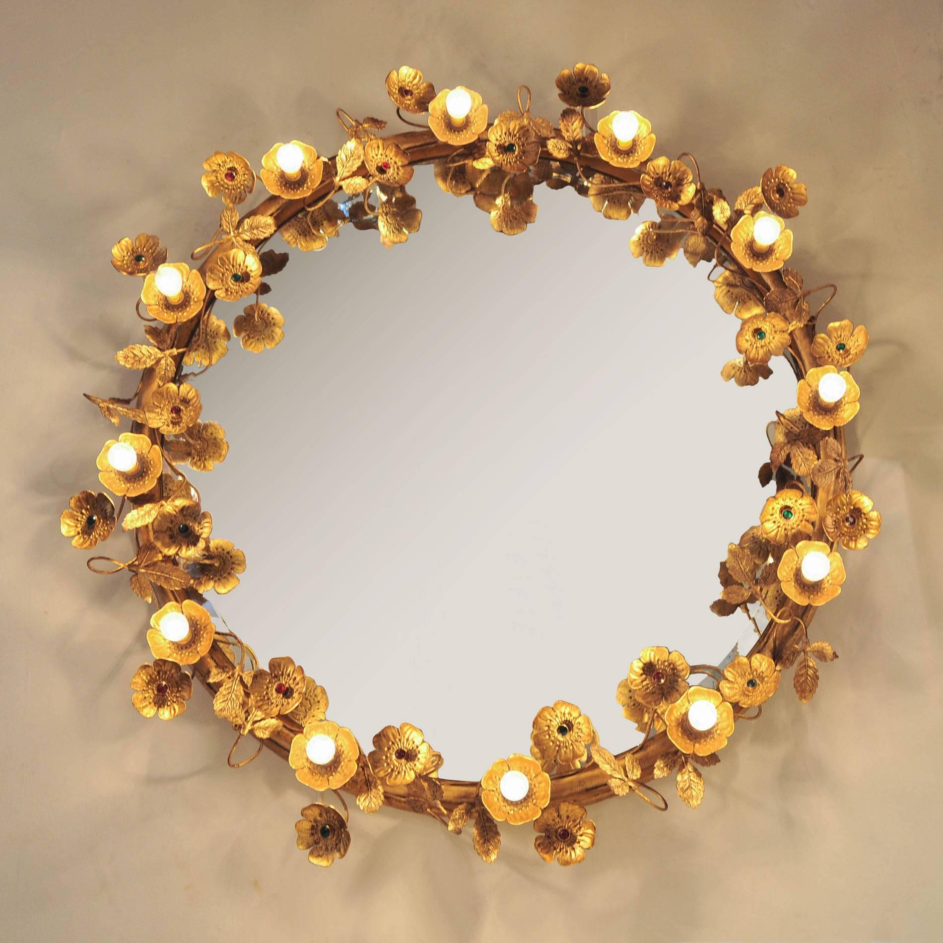 This glamorous wall mirror consists of delicate gold brass flowers and leaves that encircle the beveled mirror. Each flower is finished with a ruby or emerald centre unless it holds one of twelve subtle light-up flowers. It cannot fail to flatter