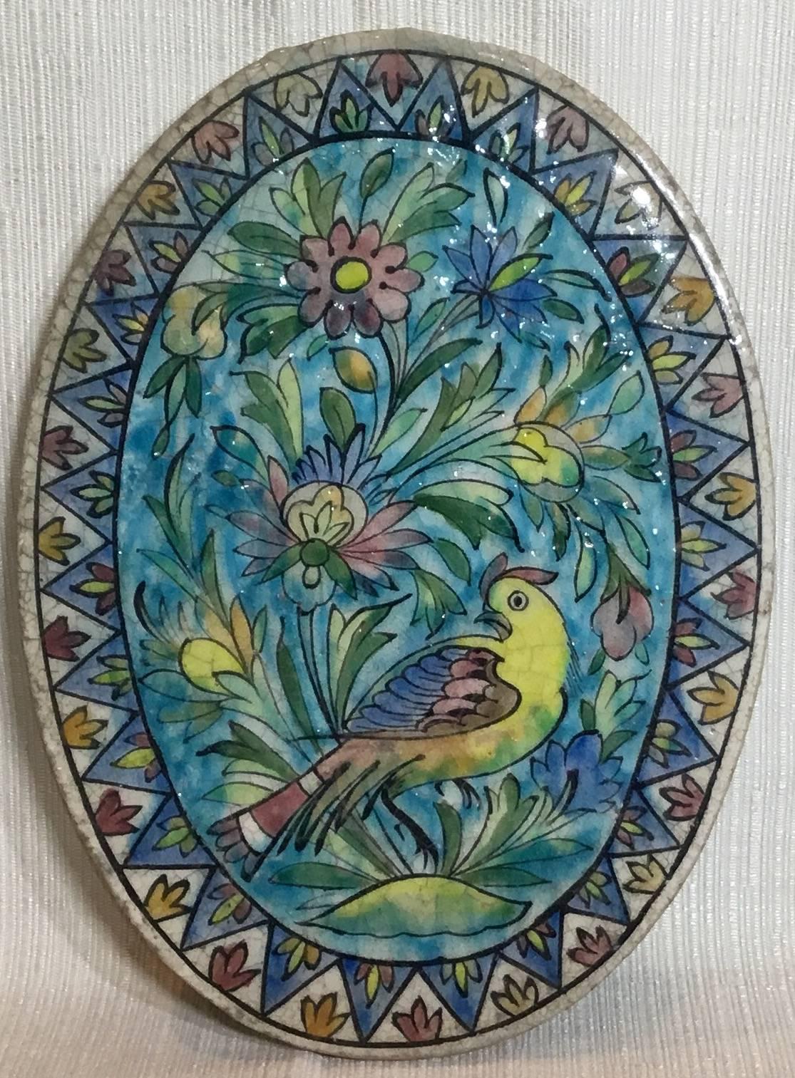 Beautiful hand-painted oval ceramic tile, with exceptional painting of bird 
Surrounded with colorful floral and vine motifs, geometric border around.