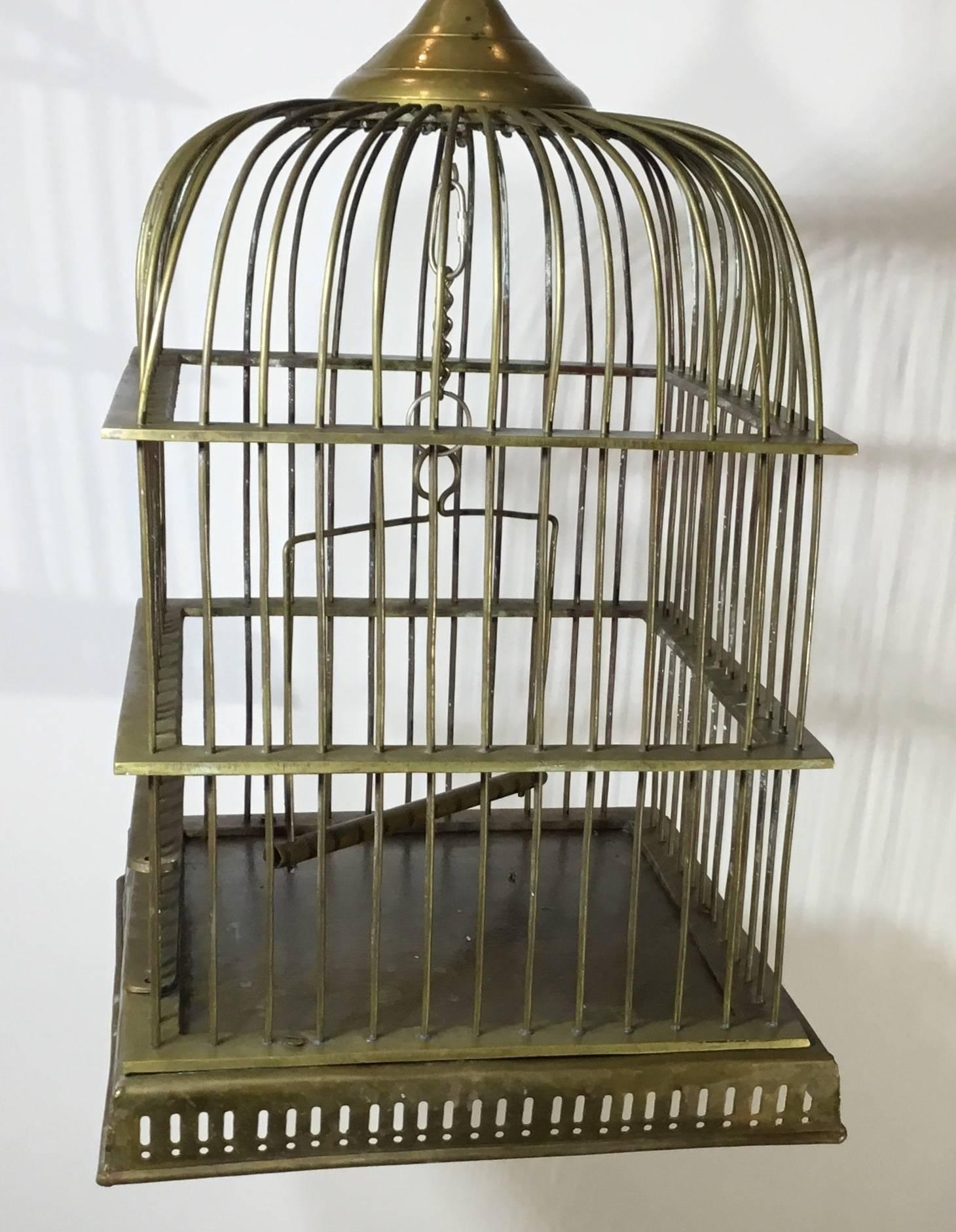 Charming antique handcrafted brass birdcage, featuring four sides body and domed top with swinging perch inside.
