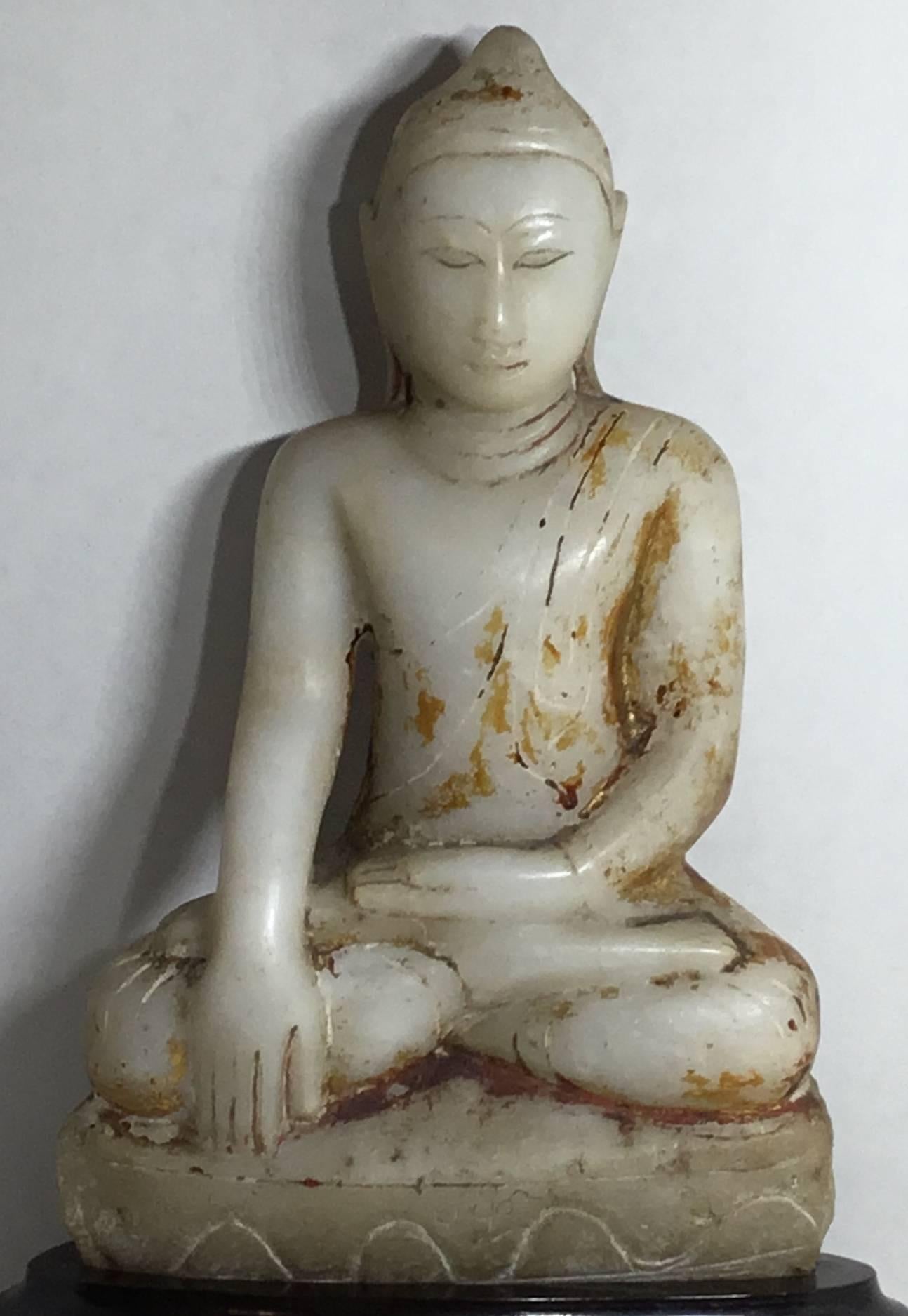 Exceptional antique Buddha made of hand-carved marble and in some parts has the original gold leaf residue, elegantly sitting on a custom-made wood base and graceful looking forward.