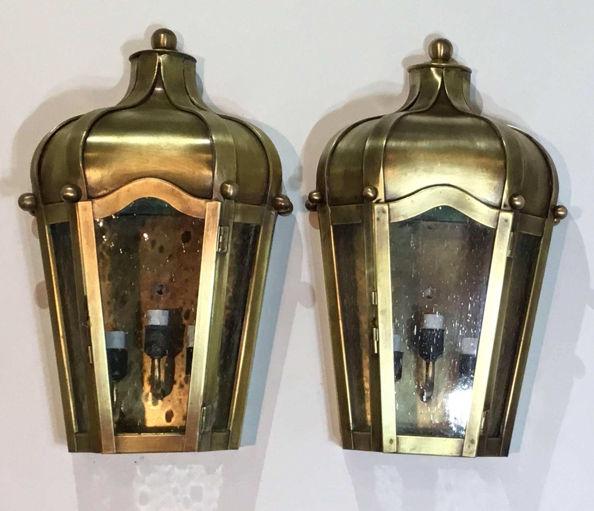 Pair of beautiful handcrafted wall-mounted brass lantern and seeded glass, artistically made and forged by hand, electrified with three 40/watt lights each, suitable for wet locations, UL approved 
Up to US code. Great decorative pair in the front