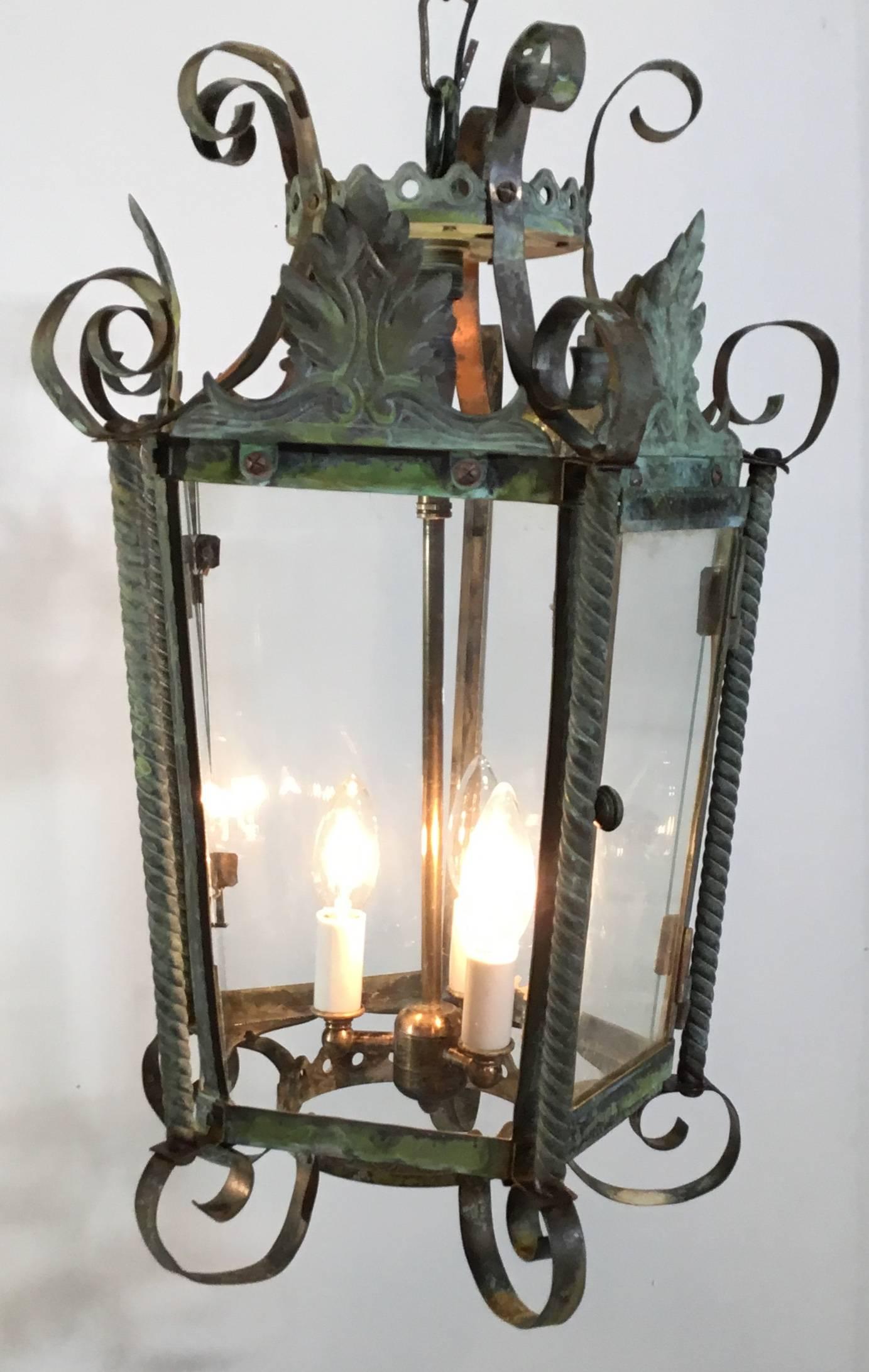 Elegant antique lantern made of twisted copper, brass columns and bronze top plate and crown.
The artistic hand-forged lantern was made originally as candle holder and later in time was added glass and electrified with new 40/watt brass stem up to