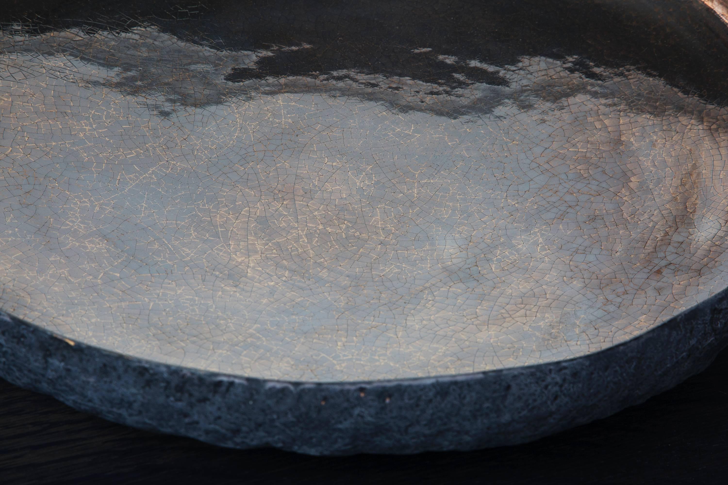 A shallow ceramic bowl with a beautiful lush mix of gold and platinum interior and a volcanic textured exterior.

Beginning with a ball of clay, Salusti pinches it into vessels and textures them with stone fragments. After multiple firing it was