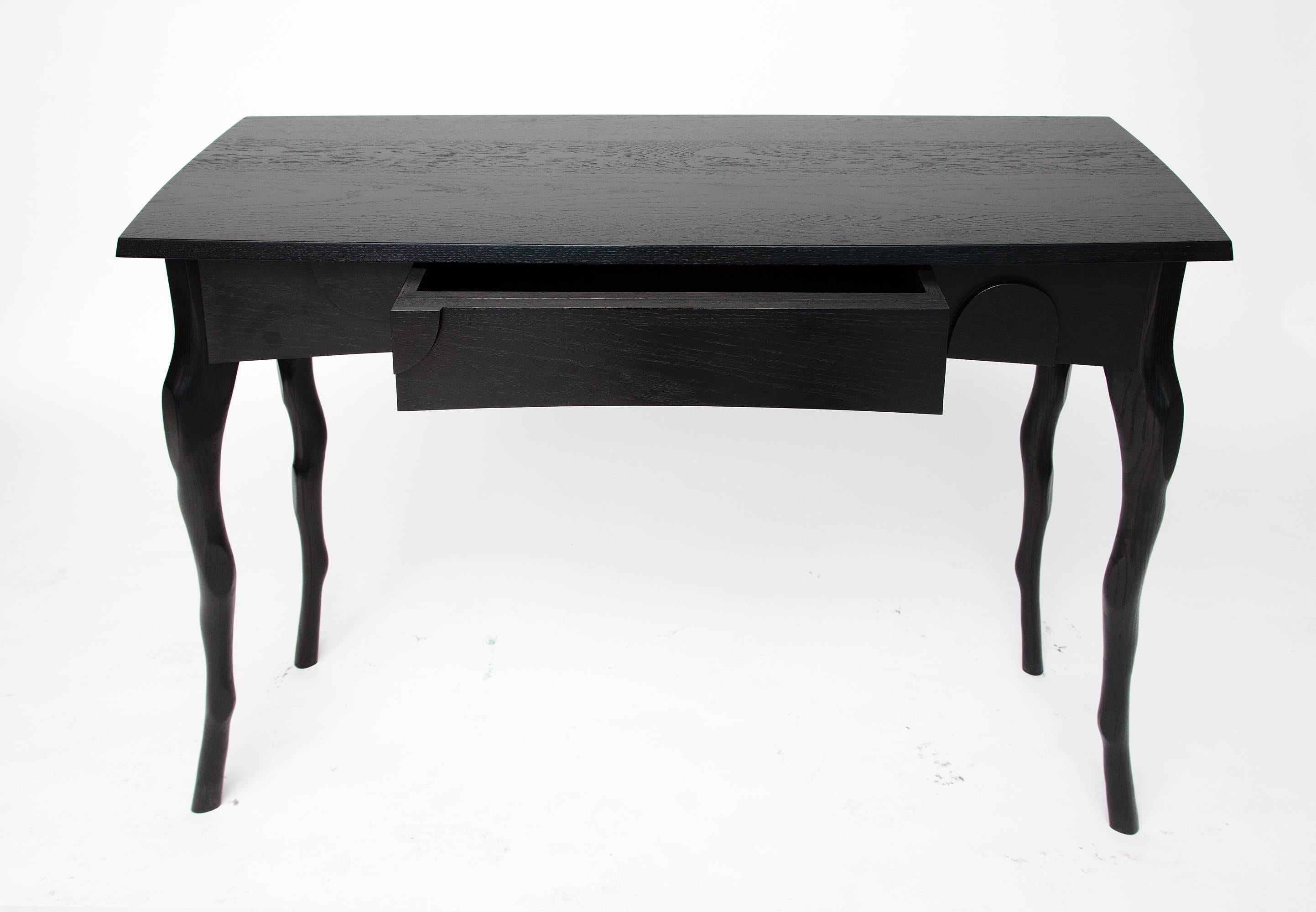 Jacques Jarrige has sculpted branch like legs to support an elegant top and slightly curved. The apron is adorned with his signature facets and has a central drawer. The oak is stained with the lush Napoleon III black stain leaving the veins of the