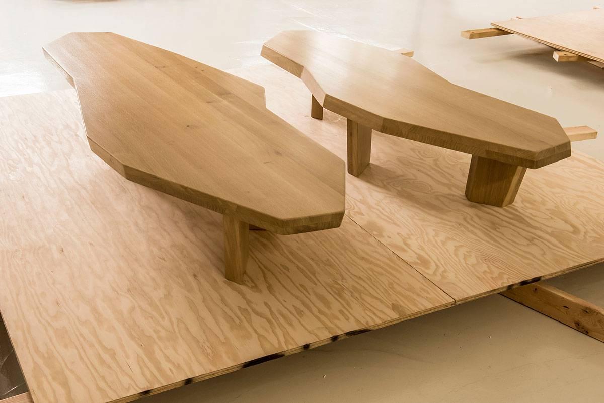 A set of two coffee tables sculpted in oak that can be nesting or separated. The legs are sculpted at opposite angles giving the pair a sense of movement. Similarly the edges are slanted differently. The smaller table has three legs and the larger