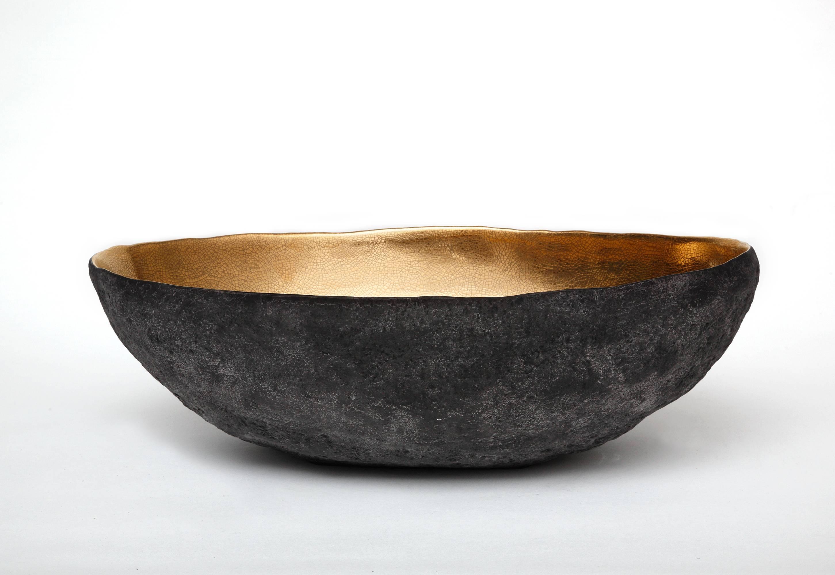 This vessel was created by Cristina Salusti. Beginning with a ball of clay, she pinches it into vessels and textures them with stone fragments. After multiple firing it was finally lustered with 22-karat gold. Its volcanic-like outer wall seem