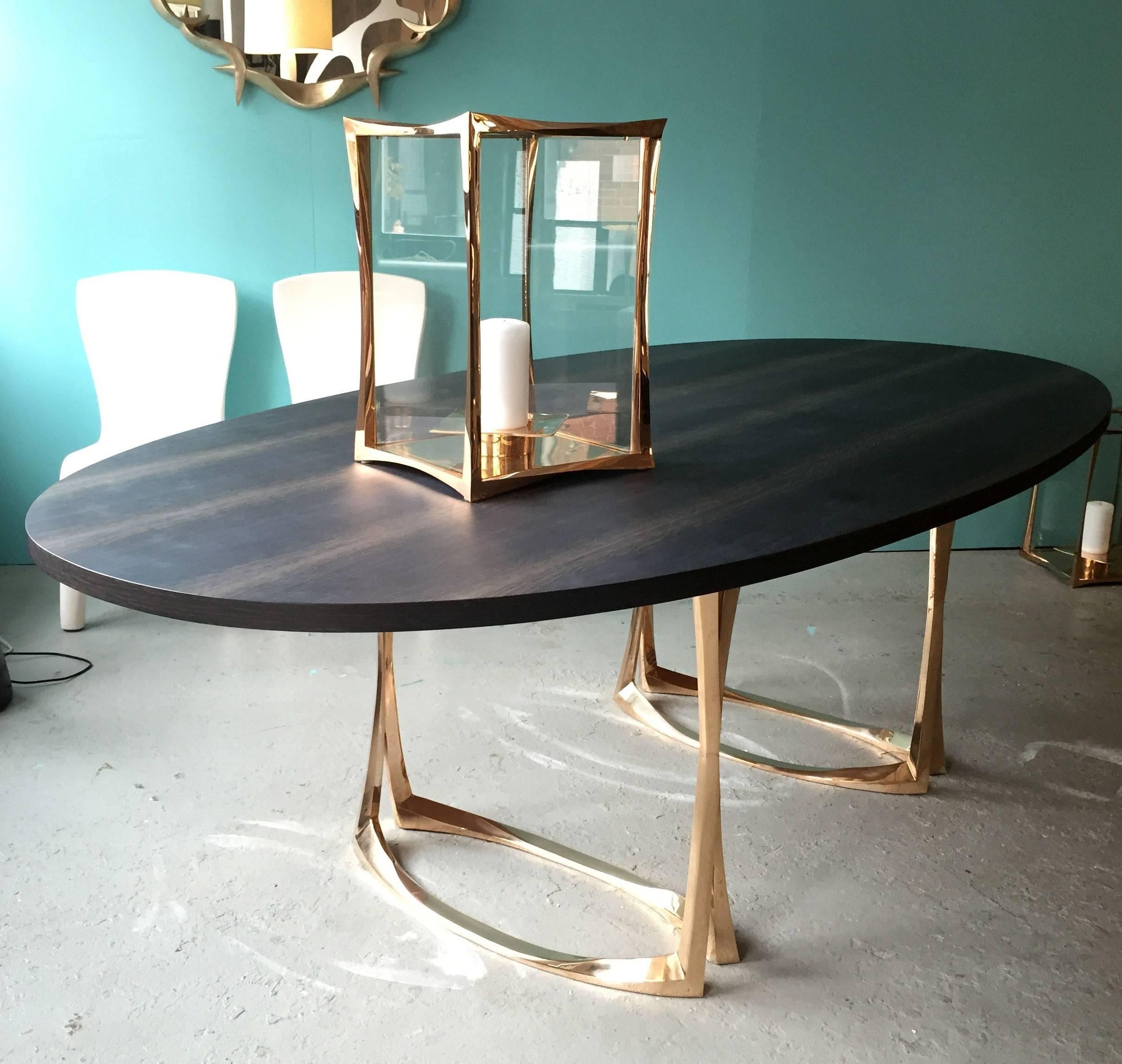 Elegant jewel like dining table by Anasthasia Millot.

The legs consist of two enlaced bronze stems forming ovals on the floor. 
The top is an oval in marsh oak.