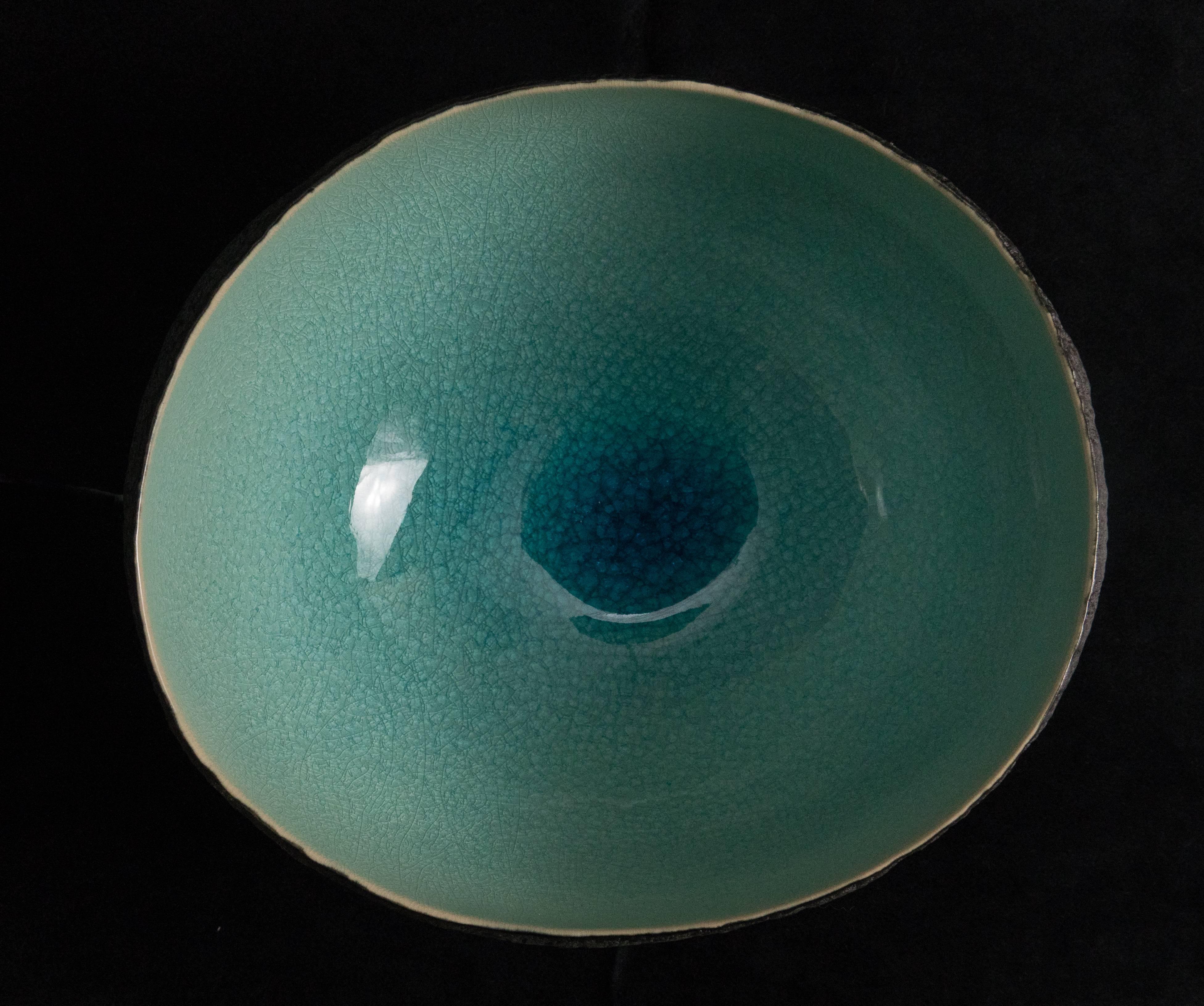 This medium size nearly round vessel was created by Cristina Salusti. 

Beginning with a ball of clay, she pinches it into vessels and textures them with stone fragments. After multiple firing it was glazed and lustered. Its volcanic-like outer wall