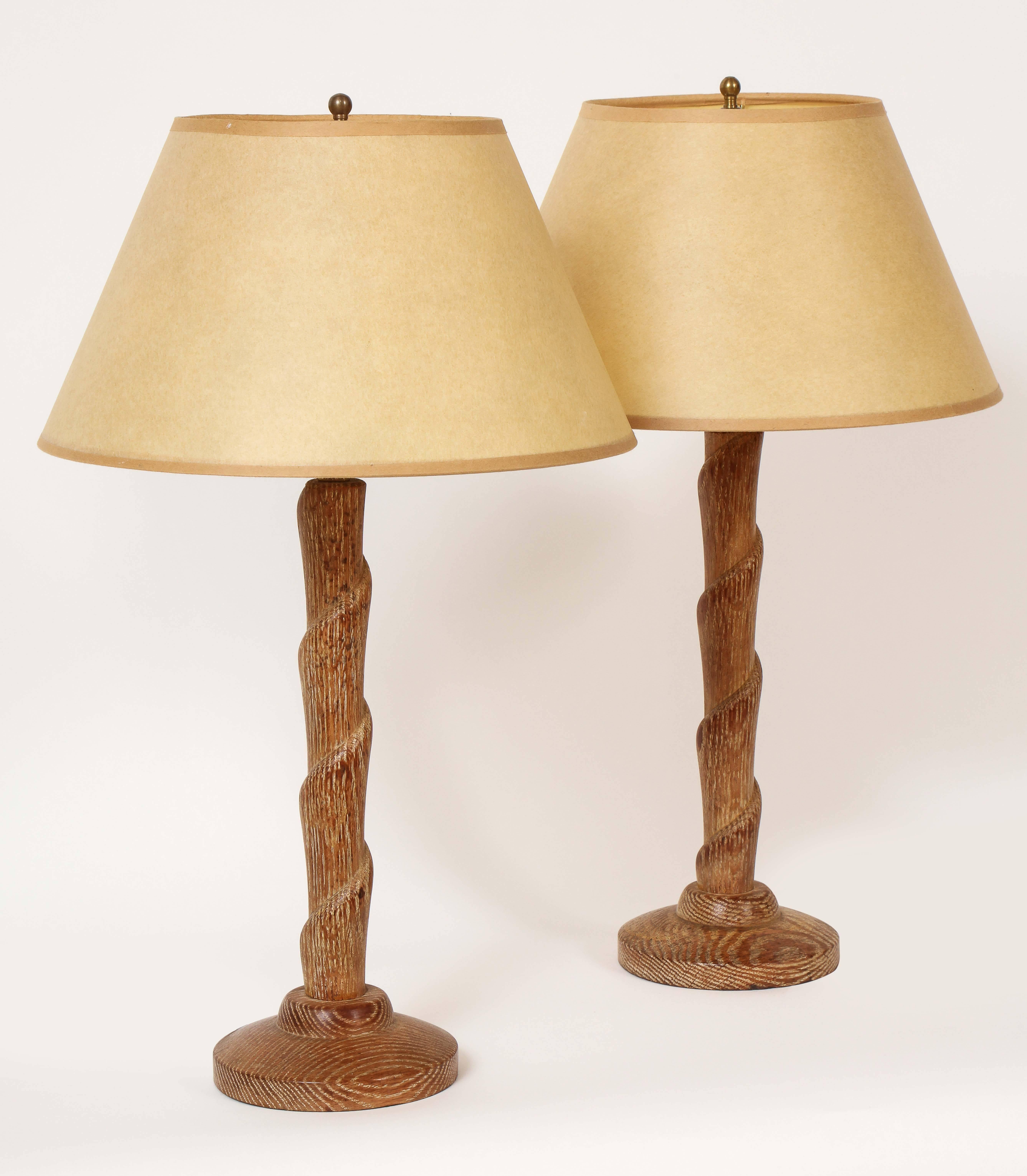 This pair of French modernist lamps, made of limed oak, each has a spirally turned stem raised on a slightly domed round base. These lamps were formally owned by the noted antiques dealer and taste arbiter, Garrick Stephenson.