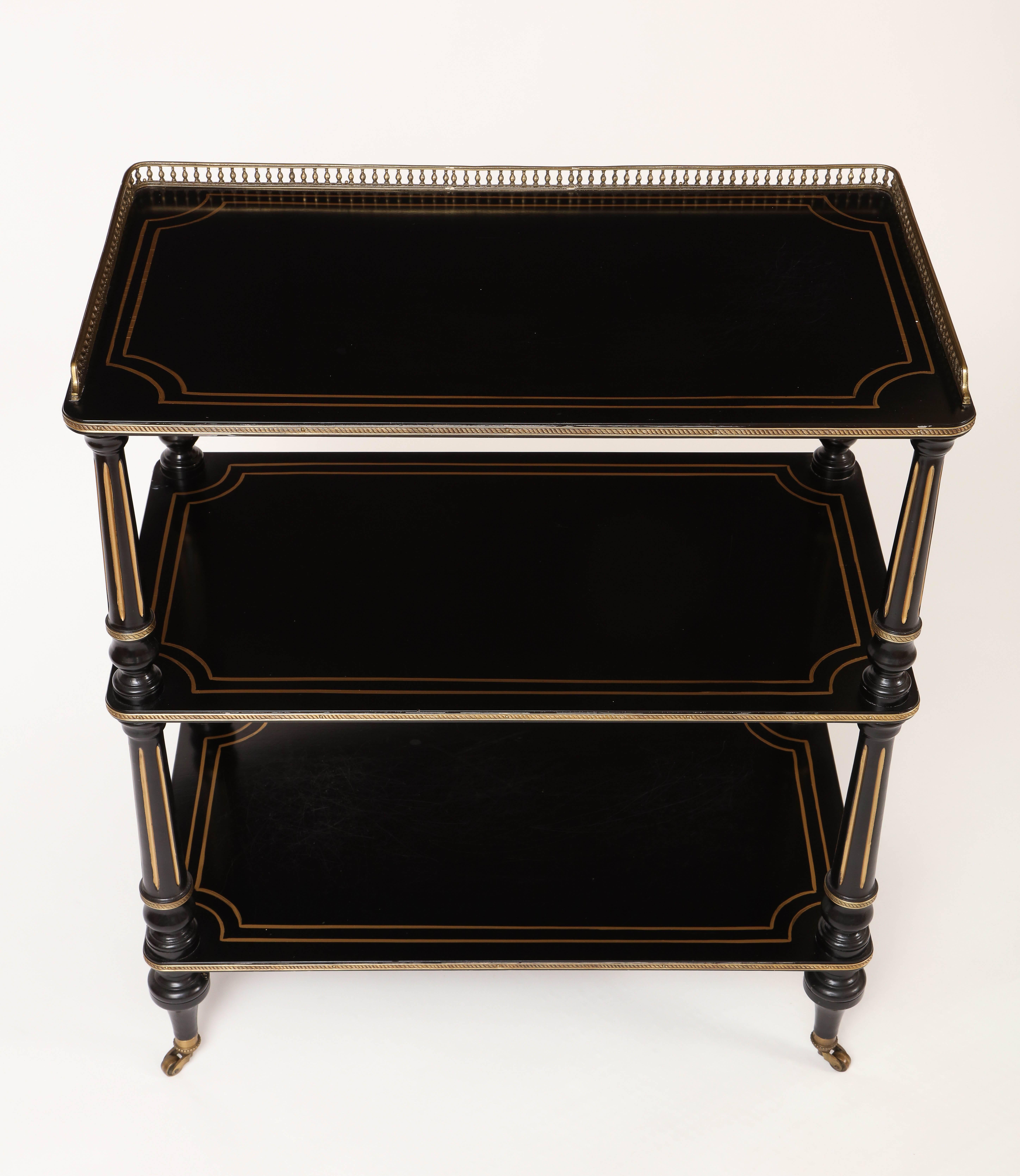This English three-tiered étagère is made of ebonized wood with parcel gilded details and gilded bronze mounts, all in the Napoleon III taste.