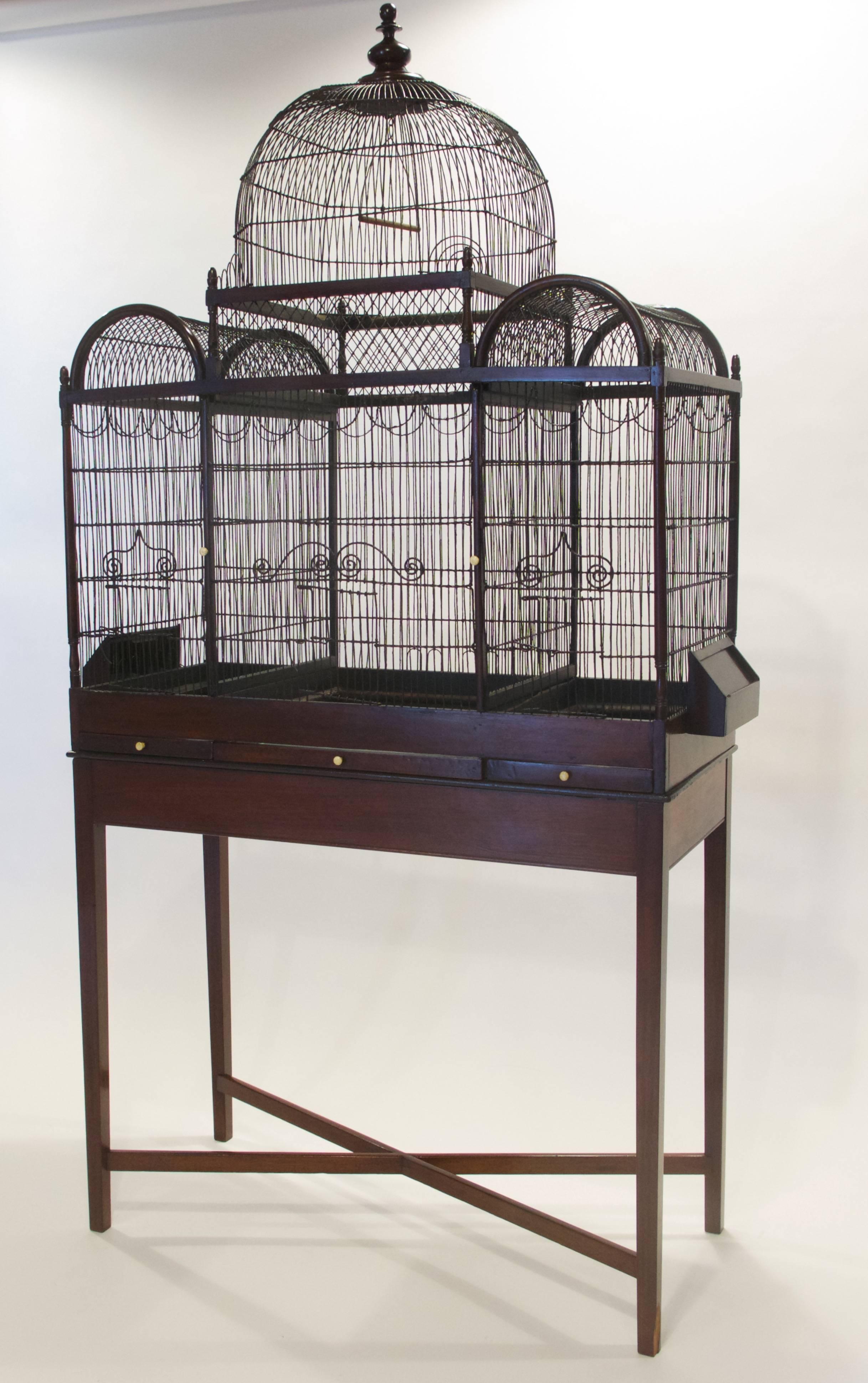 This fine and rare English George III period birdcage is tripartite in form, with a mahogany frame surrounding painted wire cages, of Orientalist form with a central dome with flanking semi circular domes. Each cage has decorative wire curlicue