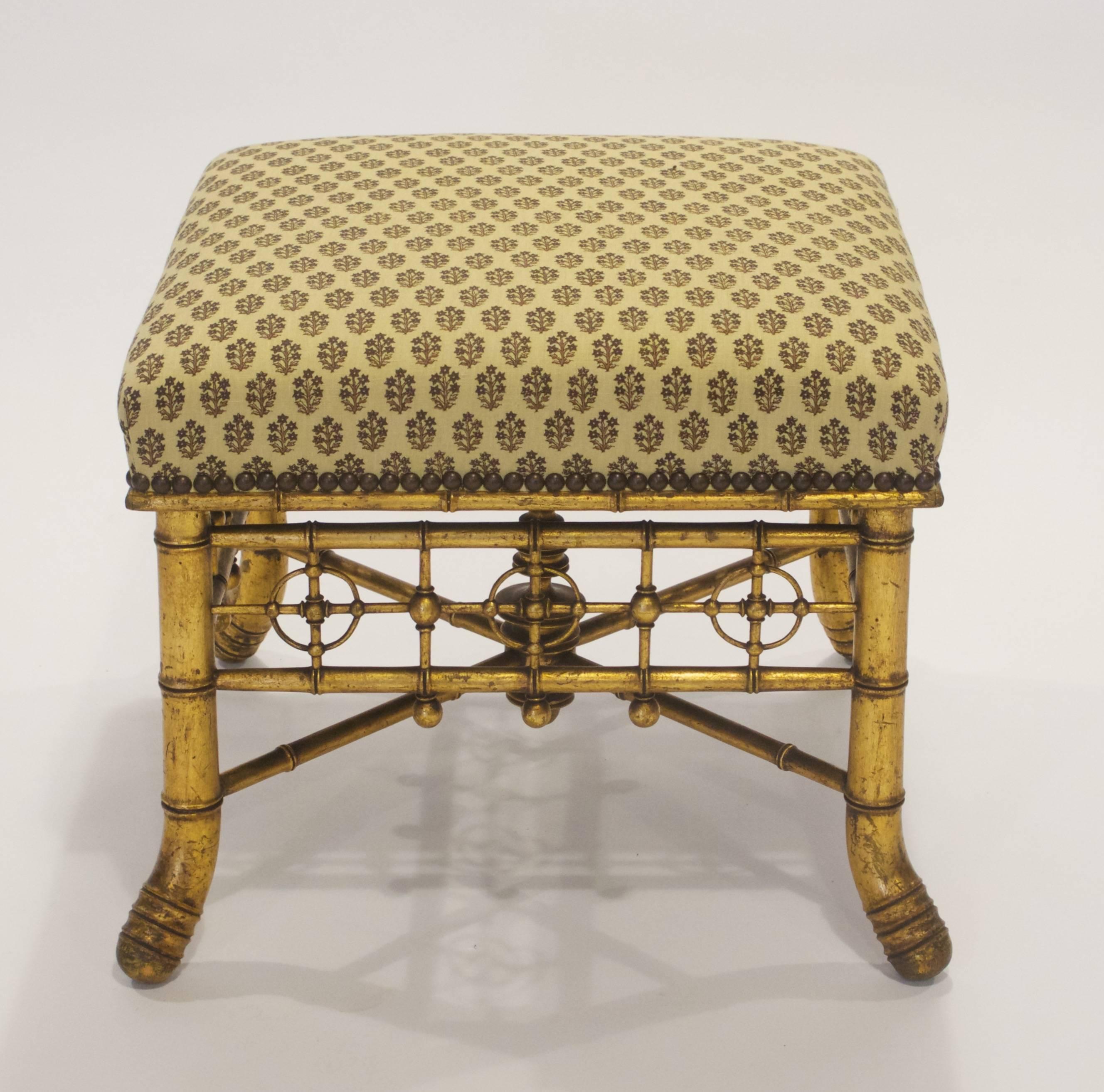 This French Napoleon III period stool has a square upholstered top above carved and gilded wooden apron, legs and stretcher, all resembling bamboo.