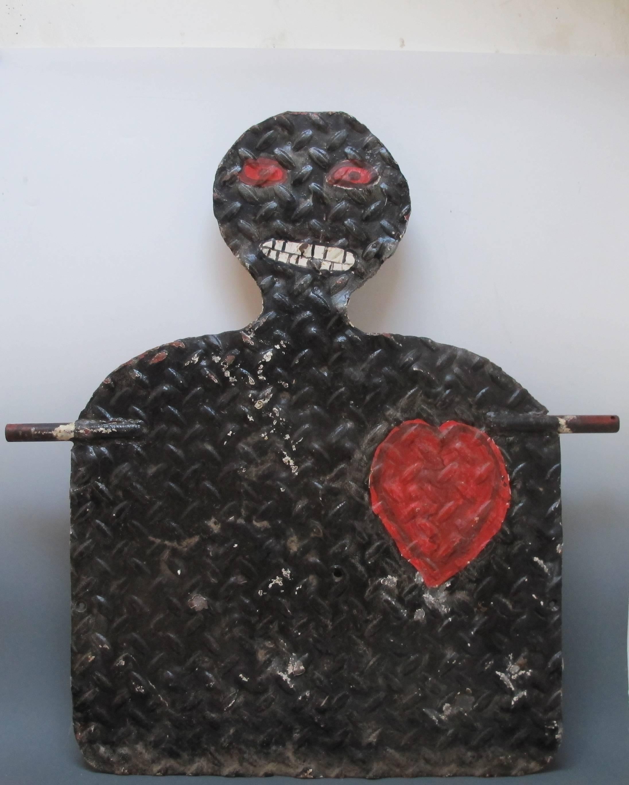 Graphic painted iron spinner target of large size. This handmade shooting gallery target was made from heavy diamond plate steel with welded rods on two sides for support ant to allow it to swing when hit. Found in Iowa, The image has the bold