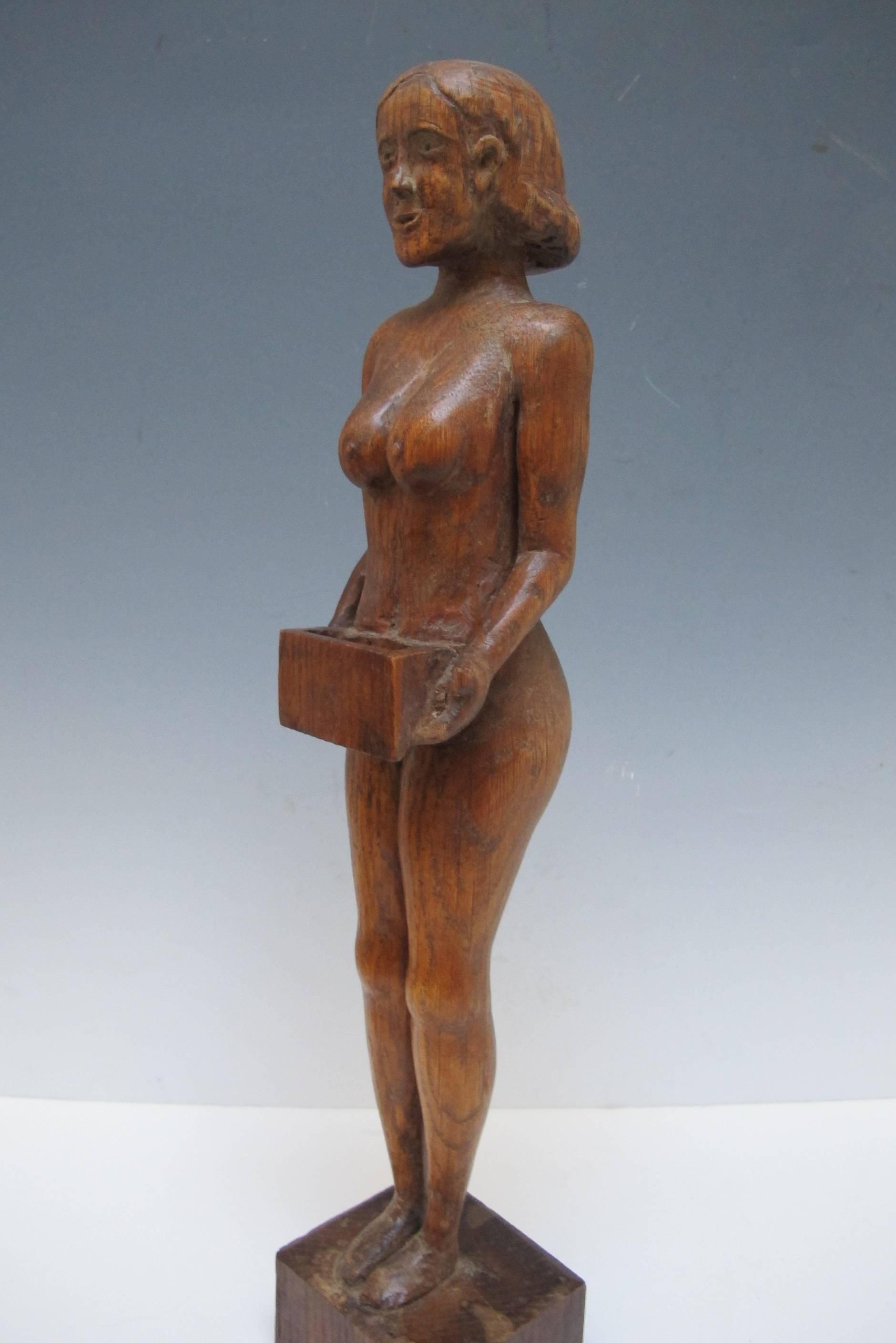 Carved oak female figure holding a box waist high large enough for wooden matches. The carver had a liking and appreciation for the female figure and skill in carving it from a single block of wood.