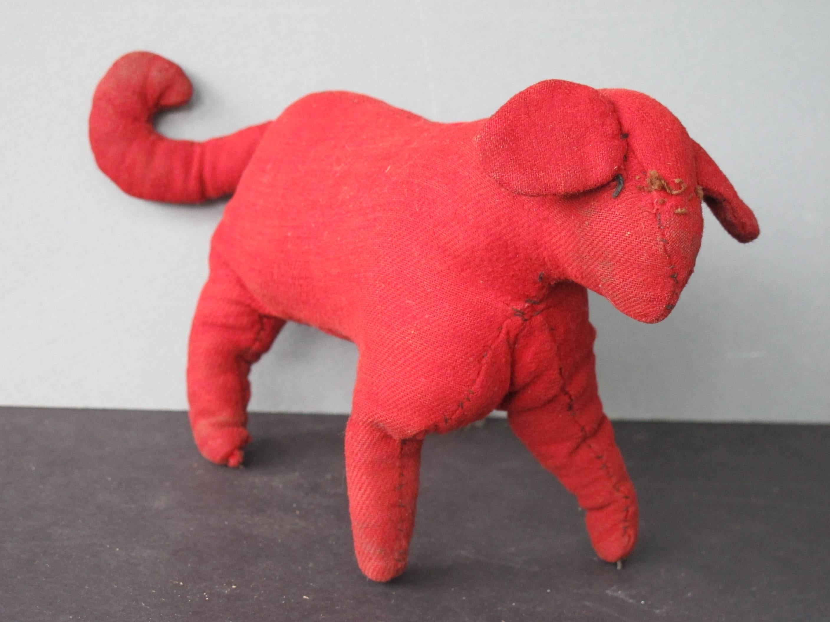 Child's soft dog sewn of soft red fabric with stitched face and floppy ears and curled tail. Homemade animal toys were beautifully made in rural America especially among the Pennsylvania Amish and Mennonites.