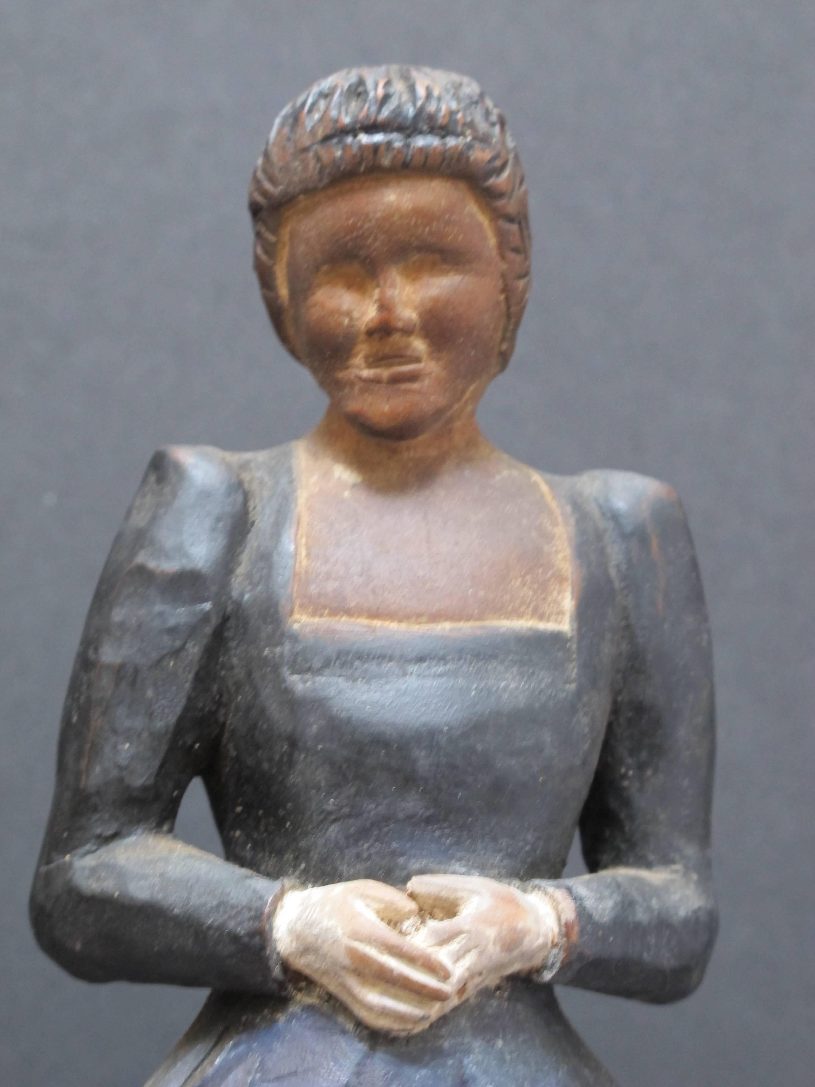 Anonymous carving of a woman with a mask like face and fancy dress. Carving marks add texture to the dress and finely carved hands with white gloves. It is the face that makes this African American carving compelling. Base included.
     