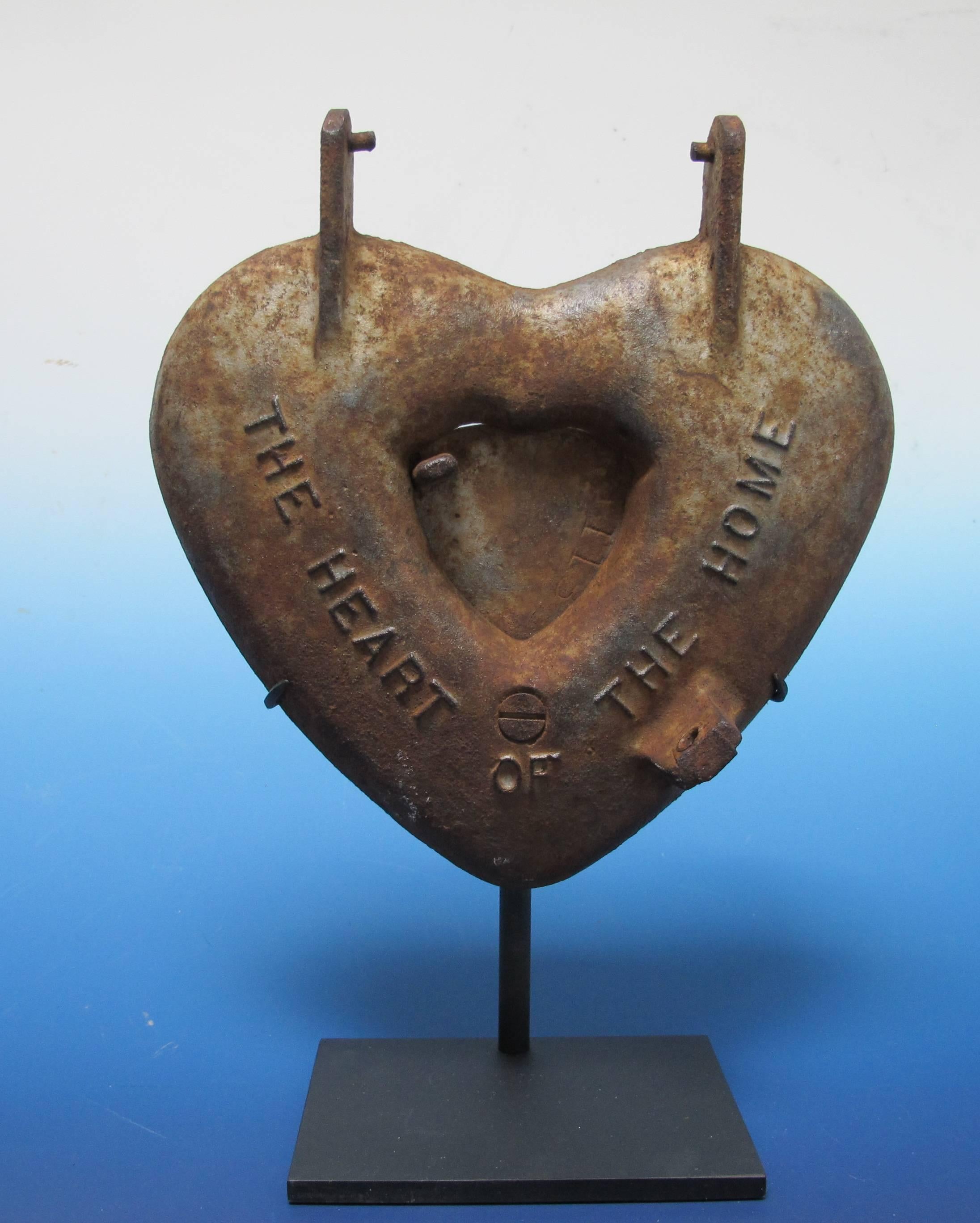 Cast iron heart shaped stove door with center heart vent. The door is unusual in having raised lettering,The Heart of the Home . Probably for an early coal burning stove from the turn of the past century. Mounted over a black metal base as work of