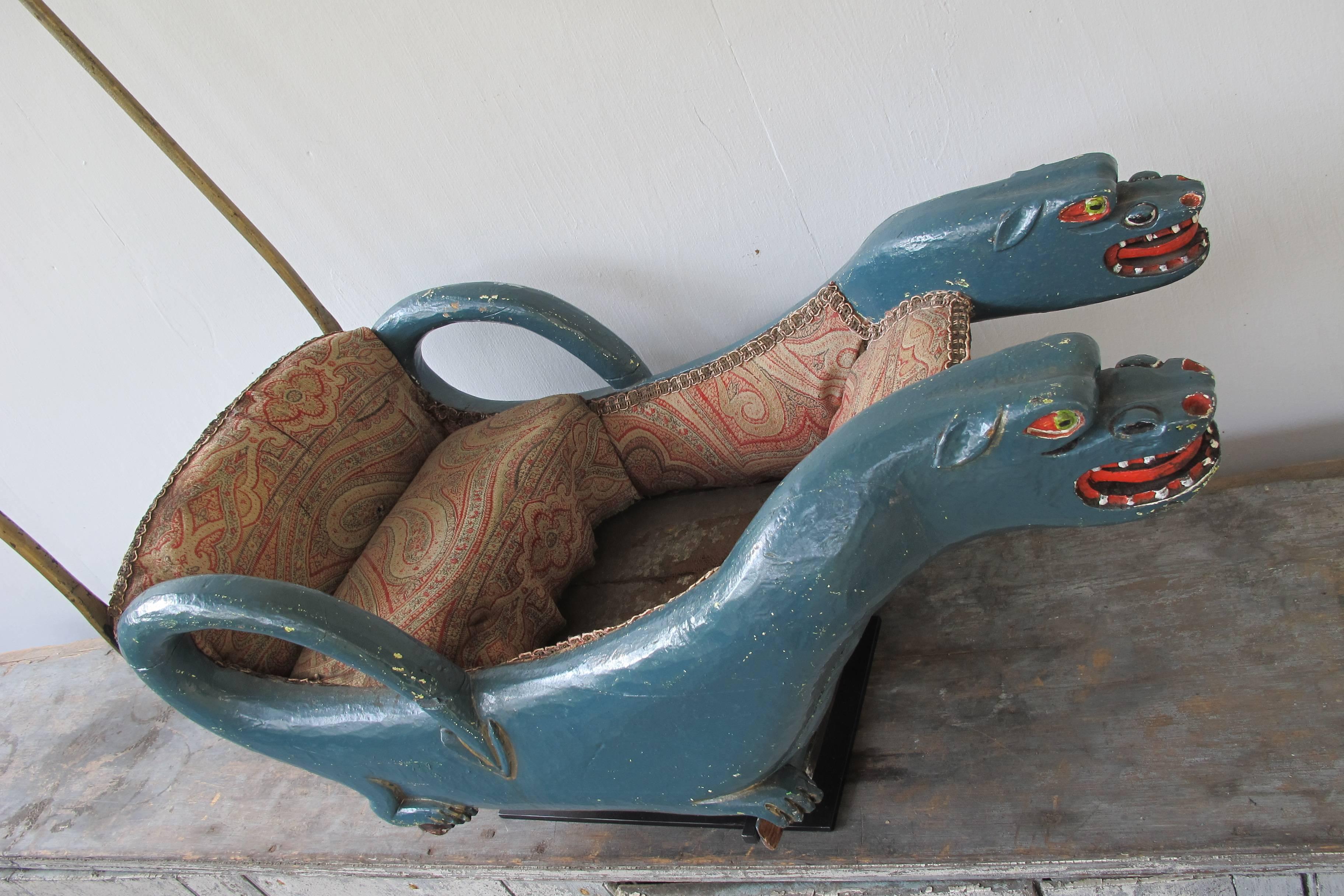 Unusual carved wood pair of dragons with a child's seat and a wood handle fixed to iron rods. The cart would most likely have had a pair of iron runners to allow it to be pushed across the ice. The other possibility is that it may have had small
