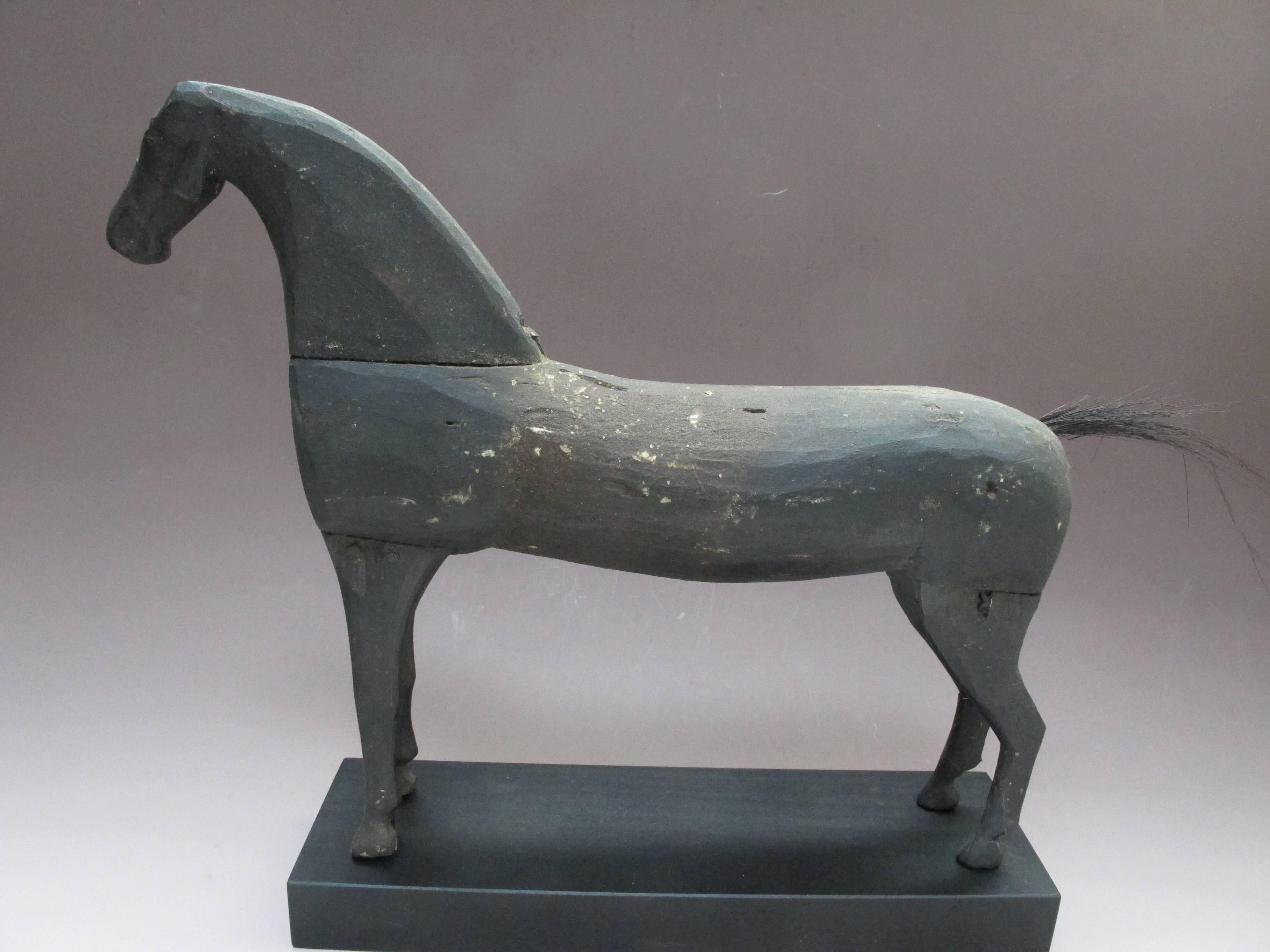 Carved and painted wood horse with joined legs and neck. Probably made for a child given its size. What distinguished it is the broad neck and elongated body.
Mounted on a black wood base.