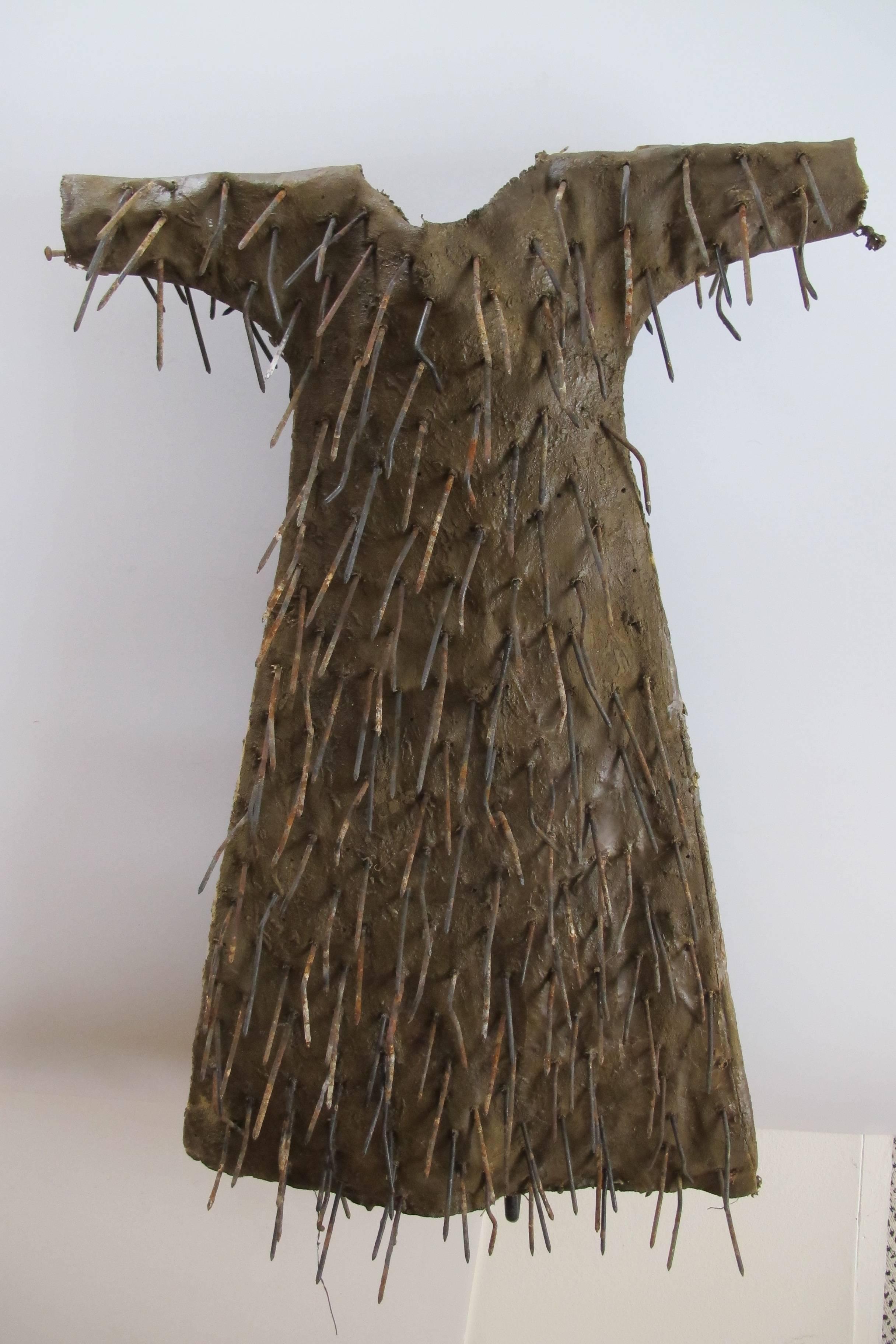 Dress as sculpture made by artist Larry Calkins. The child size dress was sewn by Larry Calkins and has old iron nails perforating the cloth. Like other dress pieces by Calkins this has a surface color for earth pigments and bees wax.
There is a