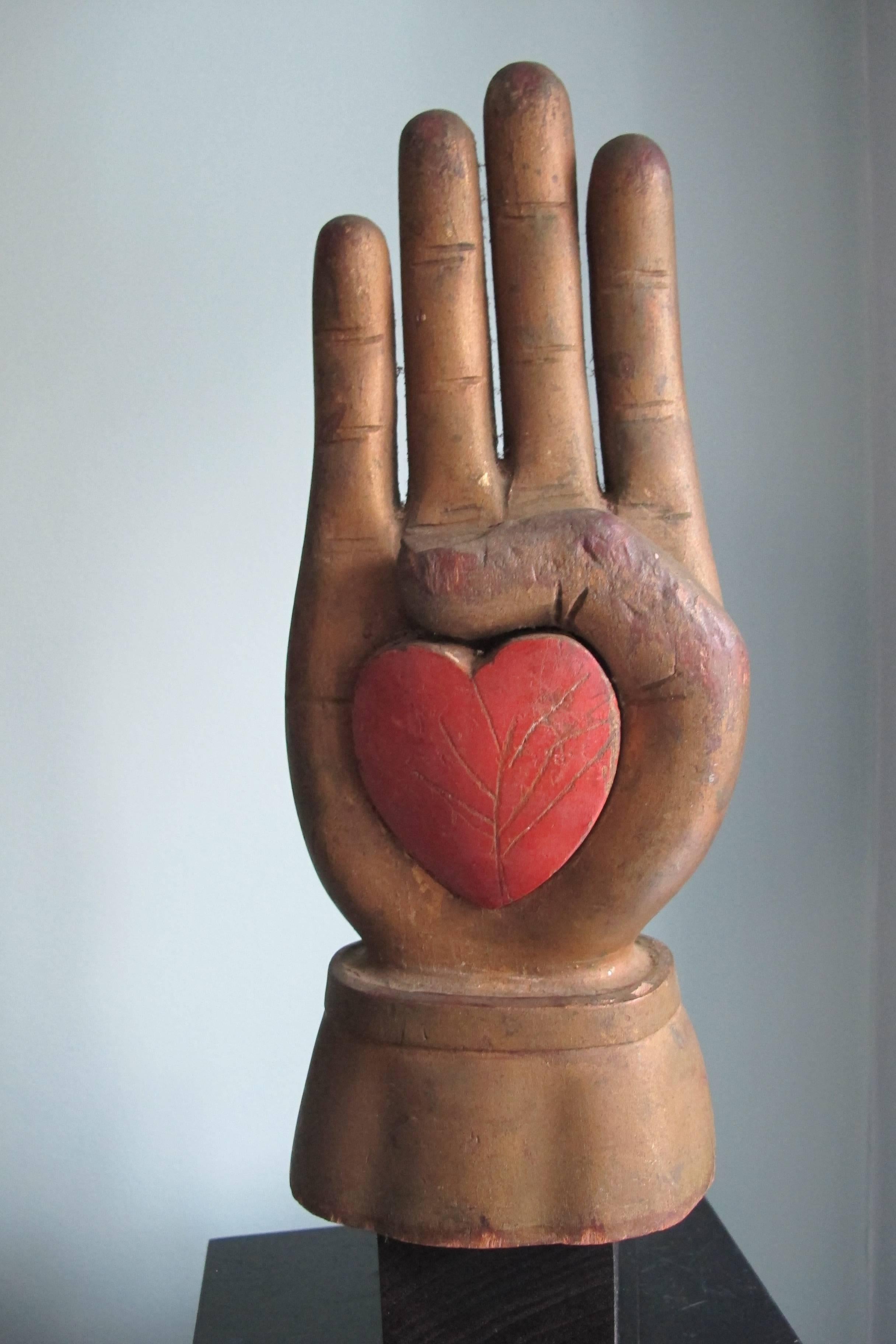 Exceptional painted wood carving in the form of a heart in hand. An iconic symbol of friendship and loving kindness. The fraternal movement was extremely important in early American society and the international order of odd fellows was popular in