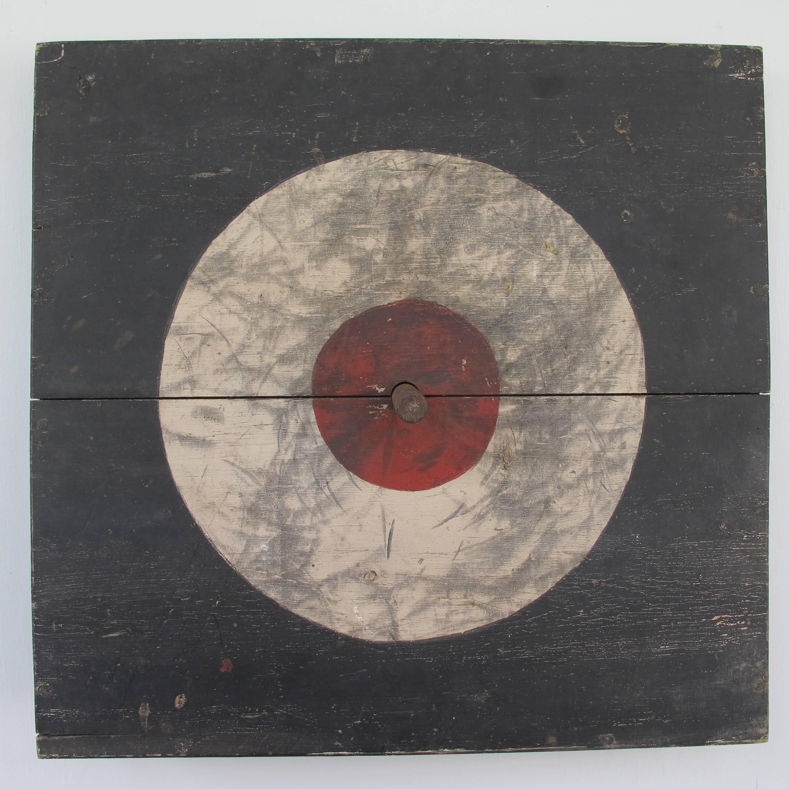 The ring toss game was designed so it could be freestanding or be able to hang on a wall. Painted black, white and red in the centre. With a wood peg coming out from the centre to catch the rings. The white ring has a history of wear which its