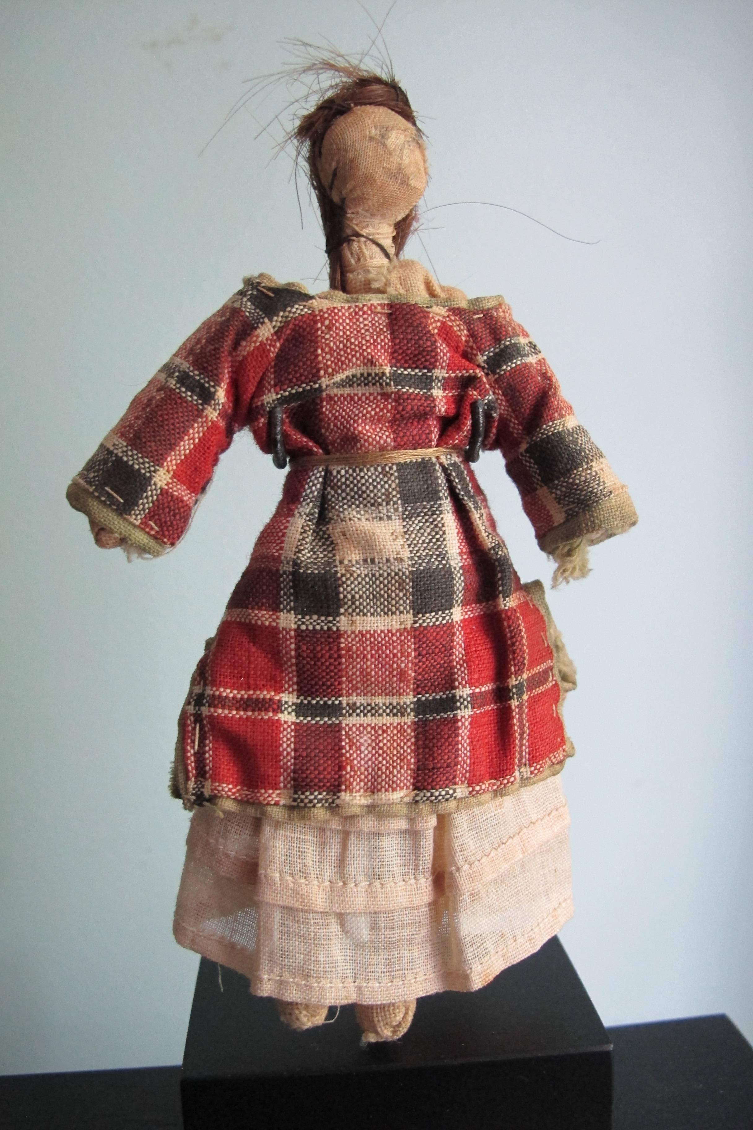From a Pennsylvania collection of cloth folk dolls comes this well dressed doll with sewn on human hair. The face is drawn on and there is in use wear to the head. There is a white cotton dress under the checked top and a slip under that. Well-made