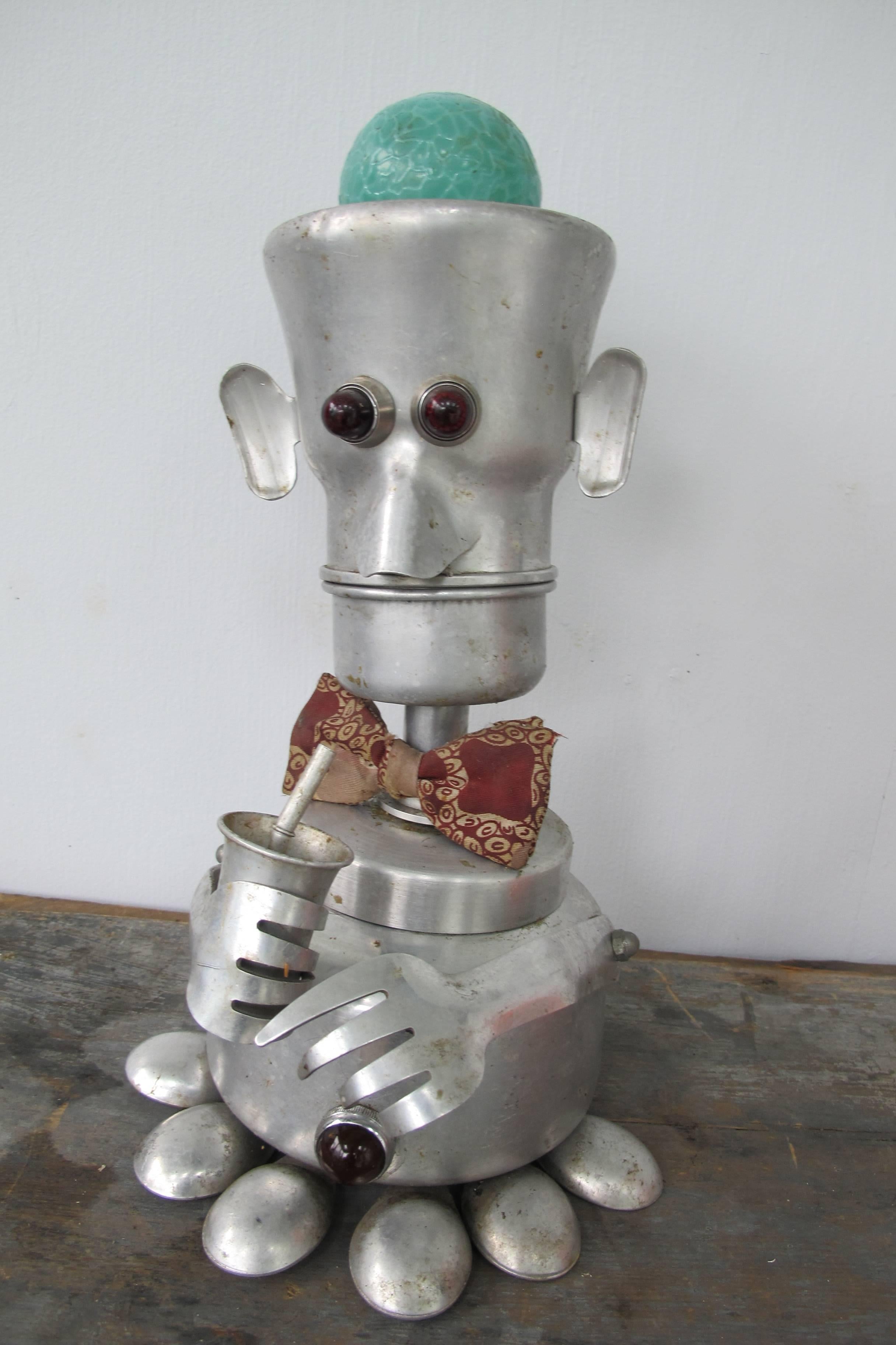 Jim Bauer has collected aluminium kitchenware for years and he assembles art pieces putting together fanciful assemblages. This figure incorporating a vintage coffee pot has colored lights that can be turned on by a switch in the back.