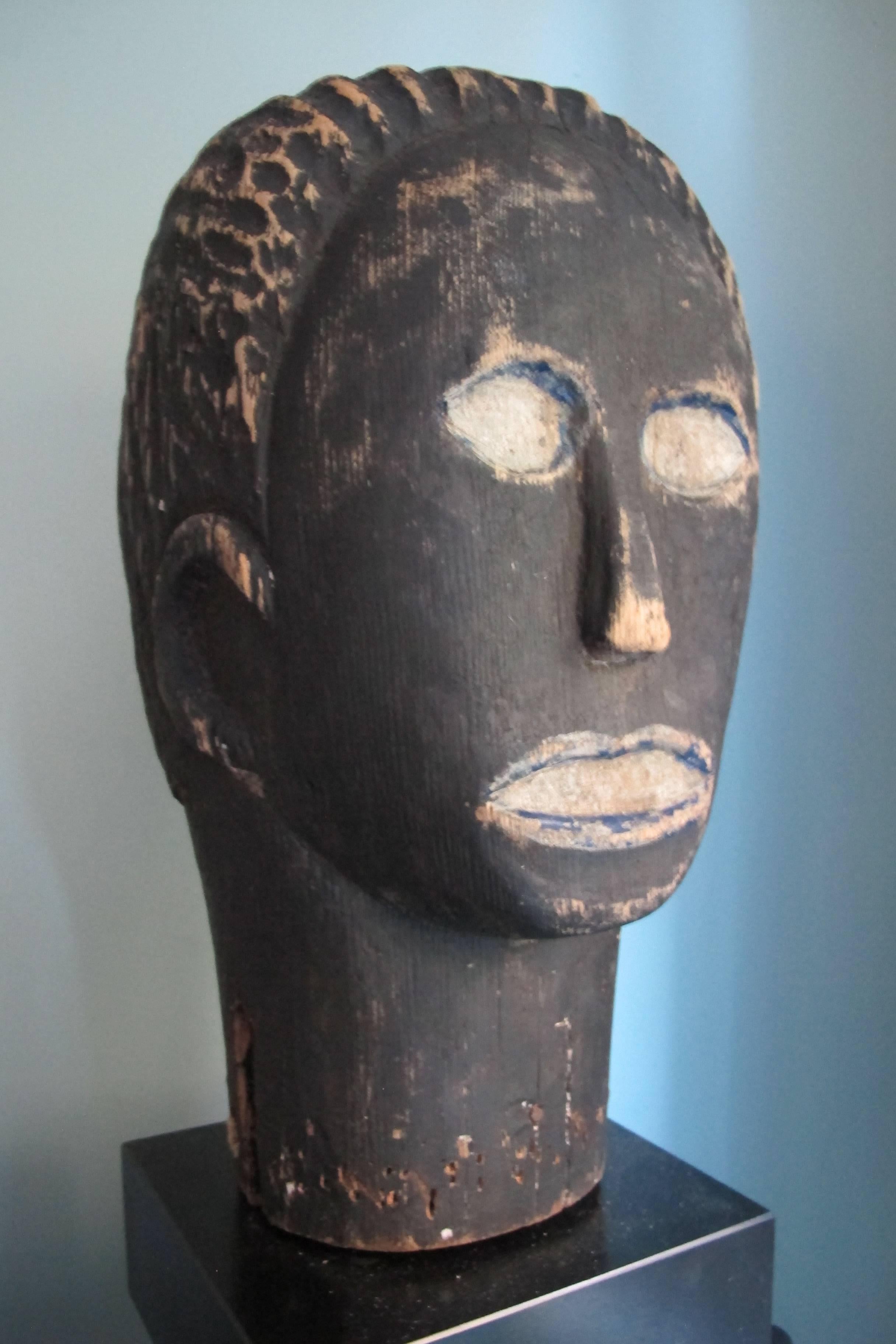 This African-American carved wood head has an unusual subtly and sensitivity from the mouth to the eyes and hair. What is most unusual is the blue paint used to outline both the eyes and the mouth. In west African areas the addition of indigo blue