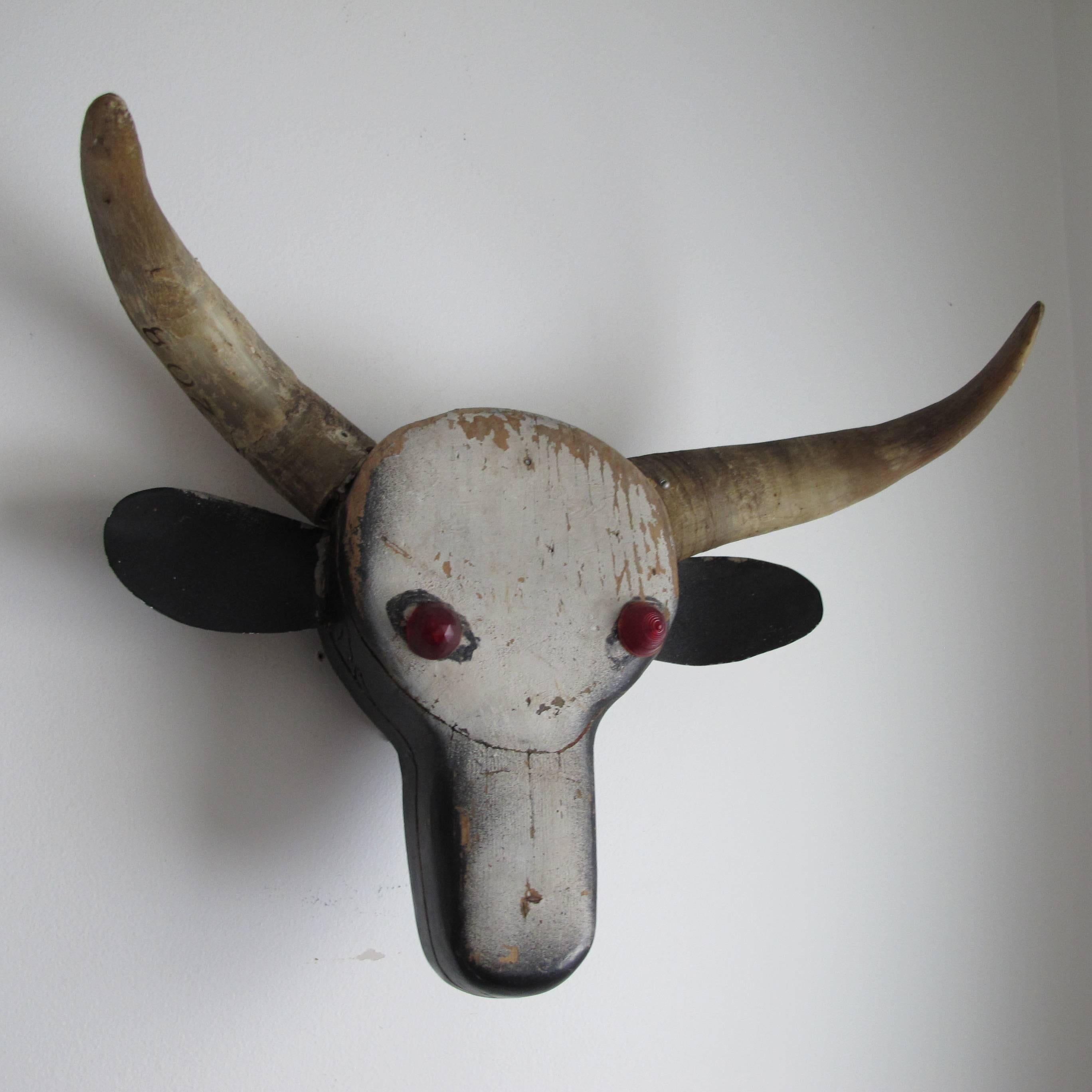 Carved and assembled wood steer head with applied horns and eyes of bike reflectors.
Made by an unknown artist to hang on a wall instead of an actual animal head.