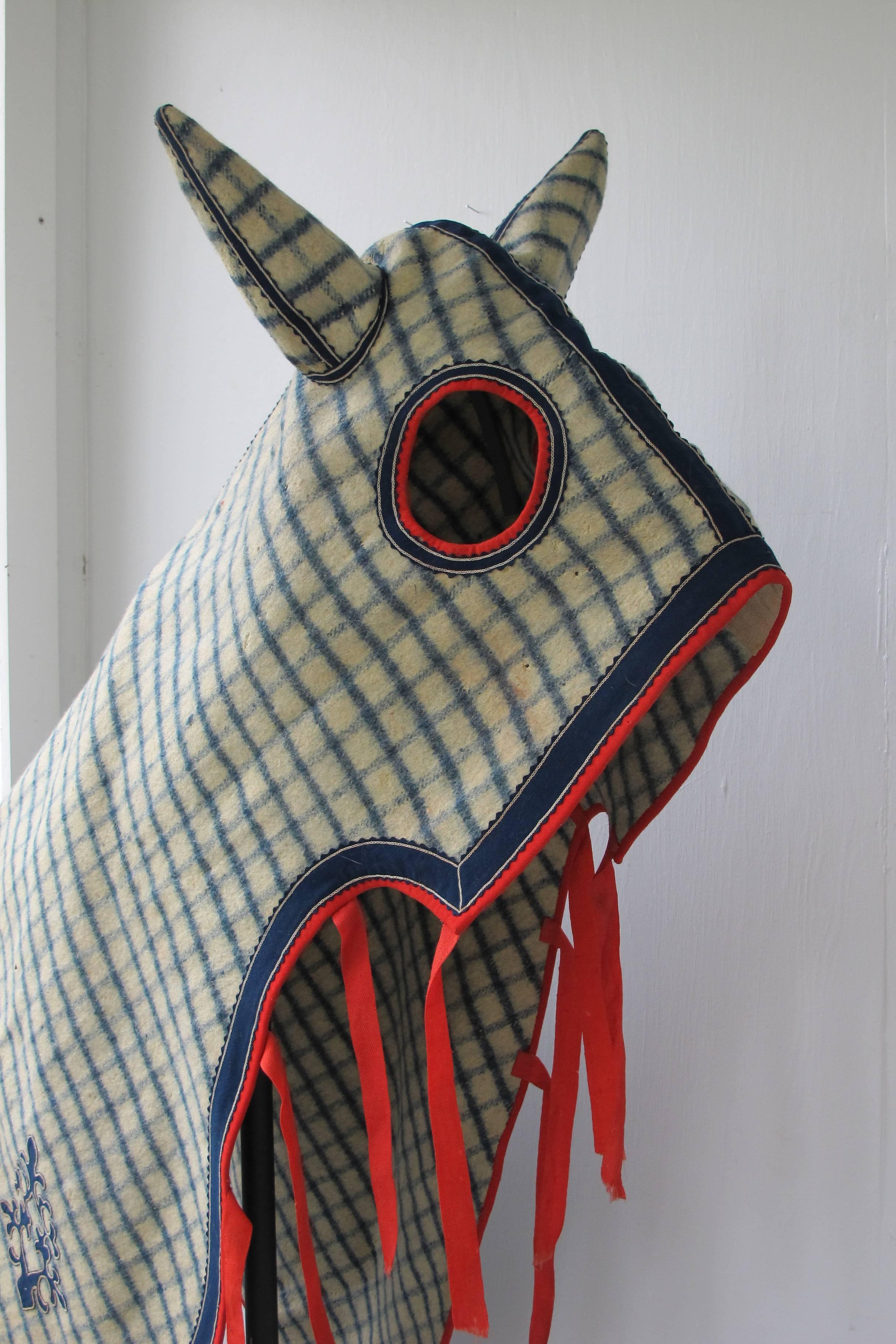 Well made wool horse blanket with head covering to keep biting horse flies away from vulnerable part of the horse. I'm told thoroughbred horses are especially irritated by the biting flies at times. This is an especially stylish horse cover with a