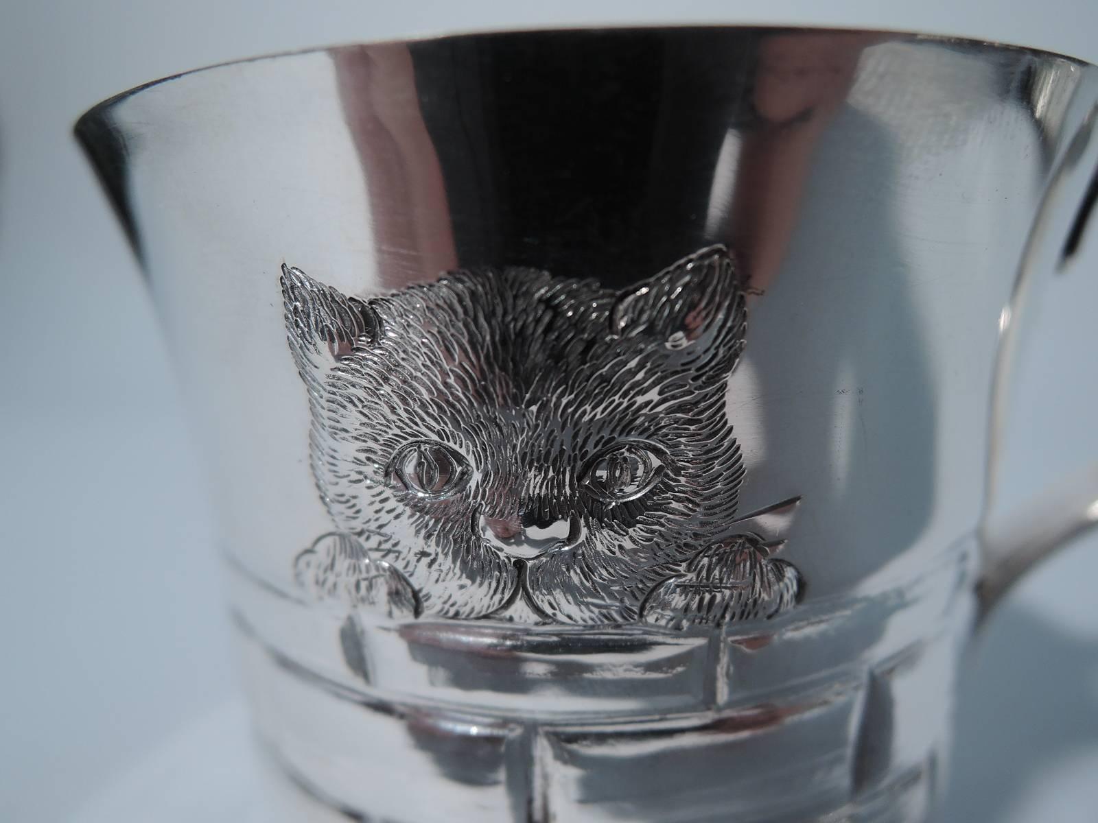 Sterling silver baby cup. Made by Tiffany & Co. in New York. In low relief, a sweet kitty cat peeps above a brick wall. Nice delineation of the soft fur, pointy ears, and sturdy paws. Scroll handle. Hallmark includes postwar pattern no. 25907.