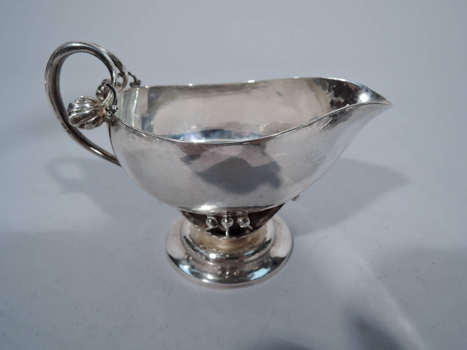 Sterling silver creamer and sugar in rosebud pattern. Made by Georg Jensen in Copenhagen. Each: ovoid body supported by stamen of open blossom mounted to stepped and round foot. Handle has rosebud mount. Beautiful craftsmanship and hand hammering.