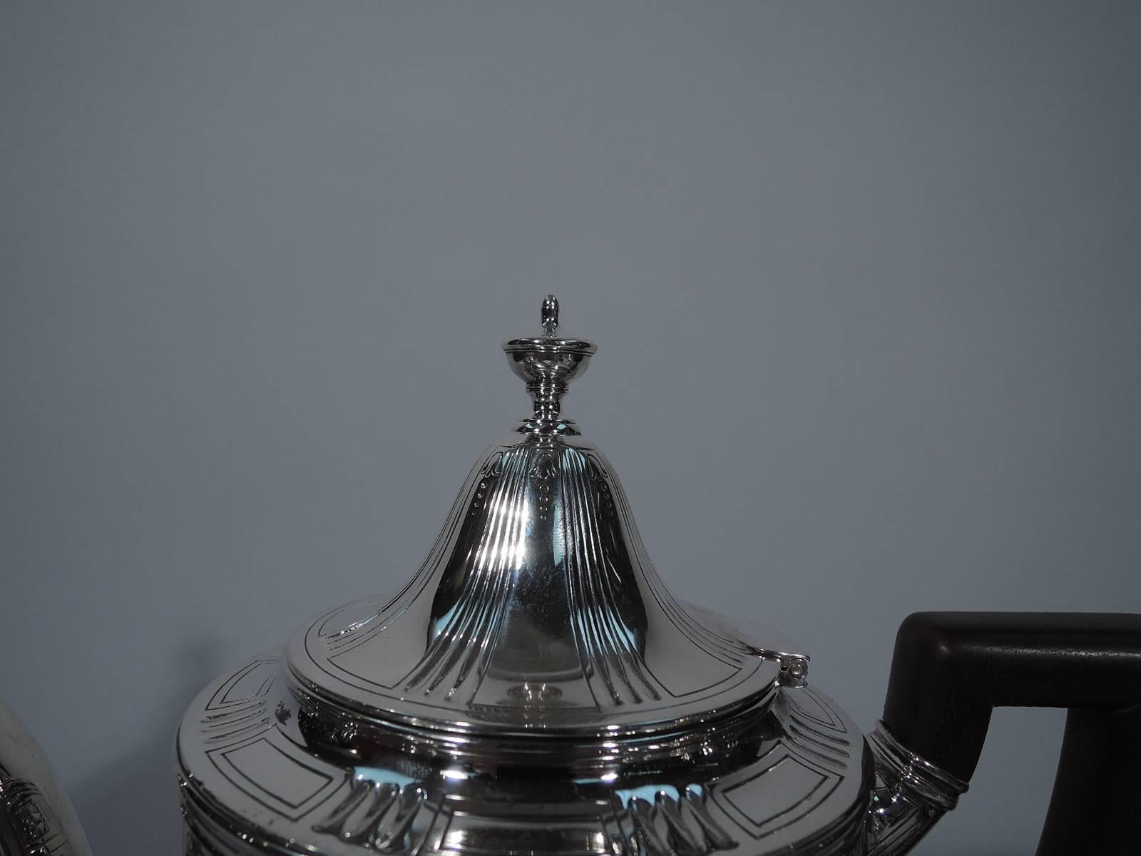 Neoclassical sterling silver coffeepot. Made by Tiffany & Co. in New York, circa 1910. Ovoid body, raised foot, s-scroll spout, hinged dome cover with urn finial, and scroll bracket in stained wood. Fluting, acanthus leaves, and pointille garlands.