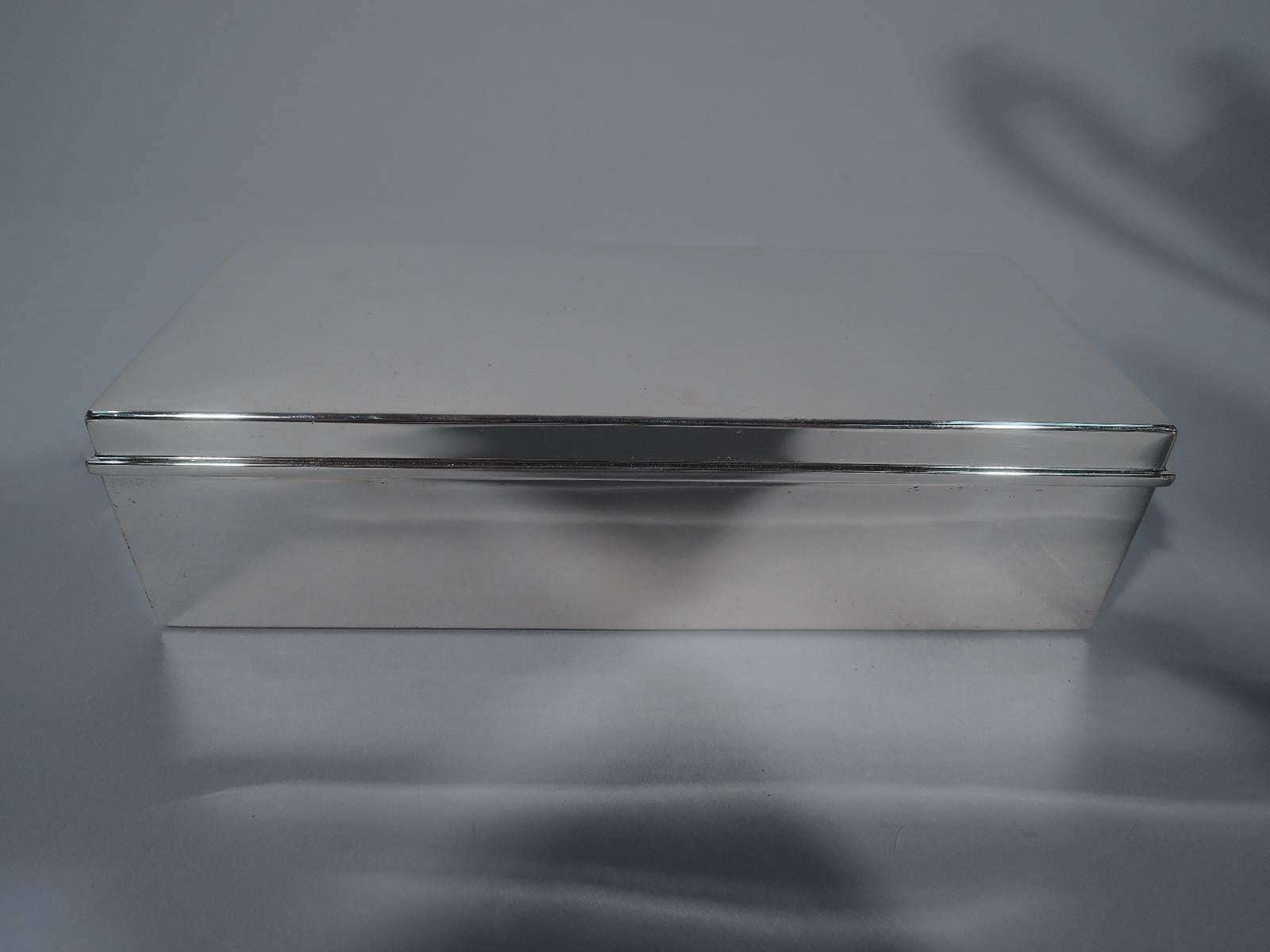 Stylish sterling silver desk box. Made by Tiffany & Co. in New York. Rectangular with straight sides and hinged cover with molded rim. Box interior is cedar-lined and partitioned. Cover interior has gilt wash. Hallmark includes director's letter M