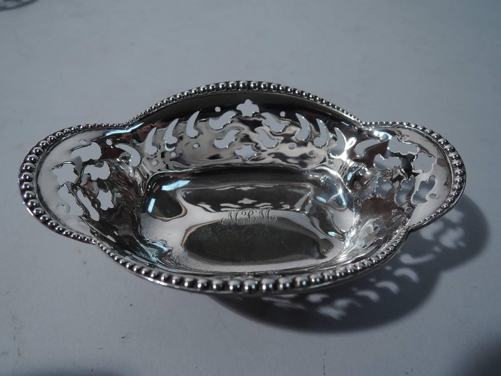 Set of 12 sterling silver nut dishes. Made by Tiffany & Co. in New York, circa 1898. Each: quatrefoil with flared and beaded rim, and pierced sides. Rests on four ball supports. Script monogram engraved to well. The pattern (no. 13732) was first
